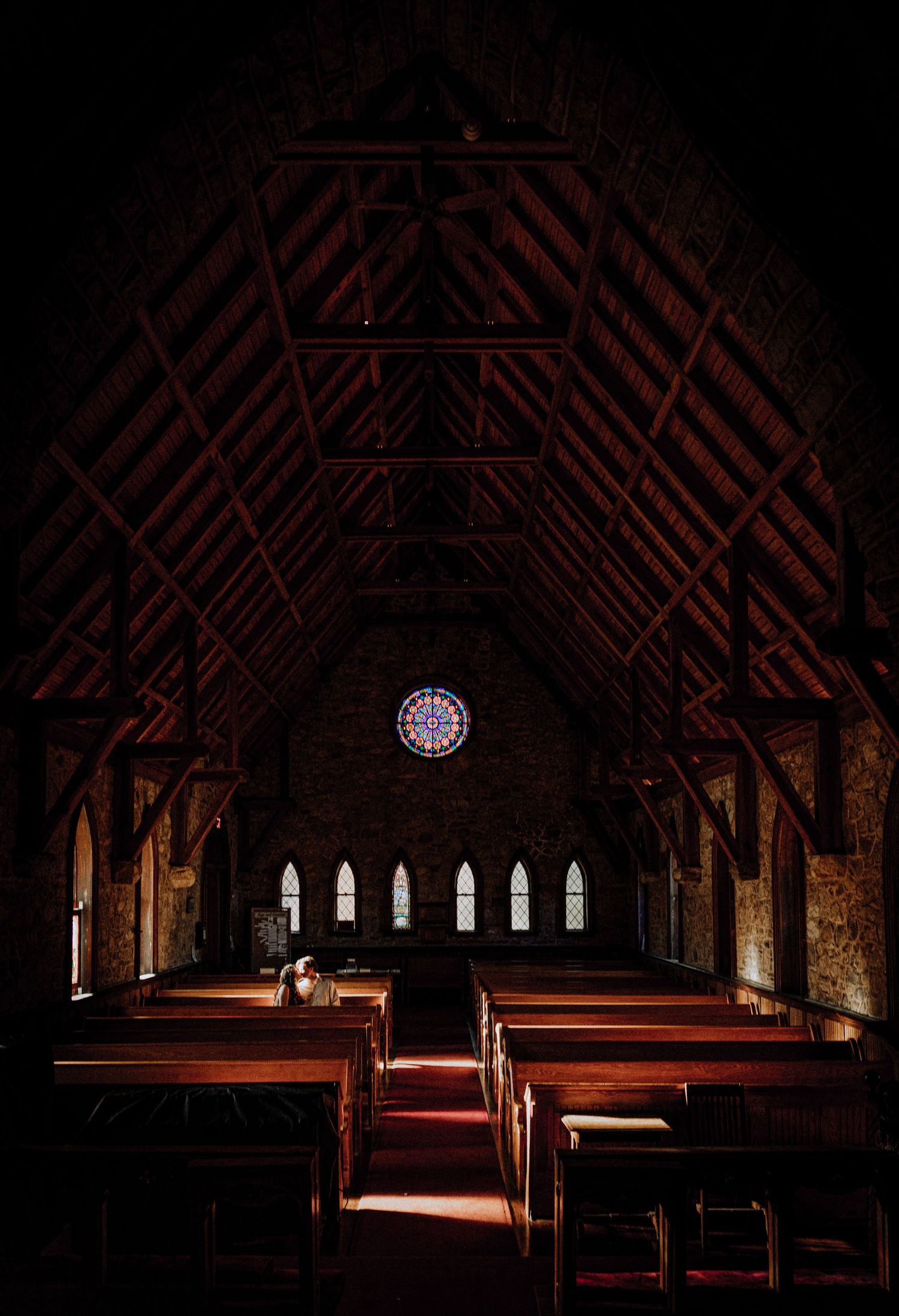 Interior of a gothic church with dramatic lighting and a rose window.