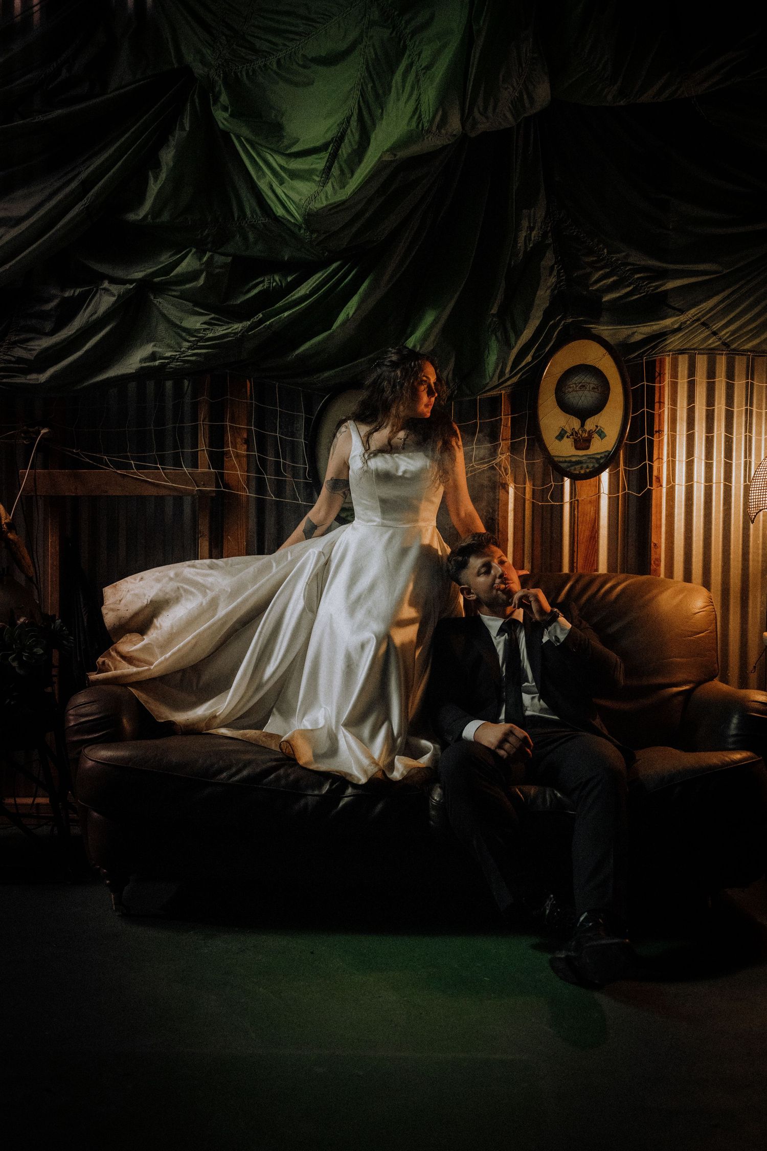 Dramatic wedding photo in dark setting with flowing white dress creating artistic silhouette.