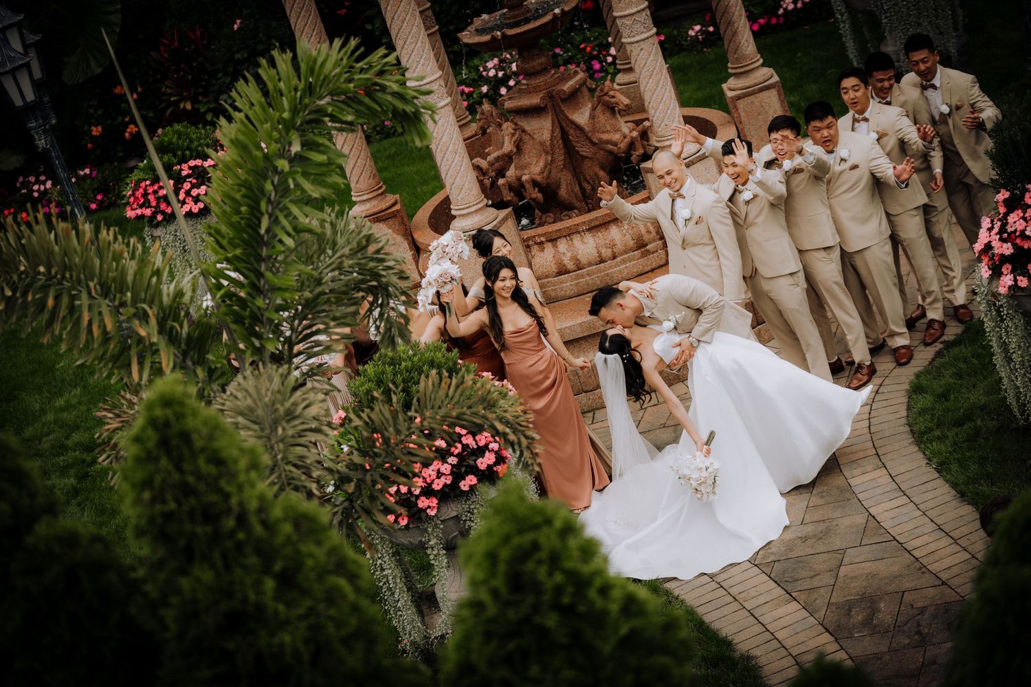 Aerial view of wedding party and guests gathered in a garden setting.
