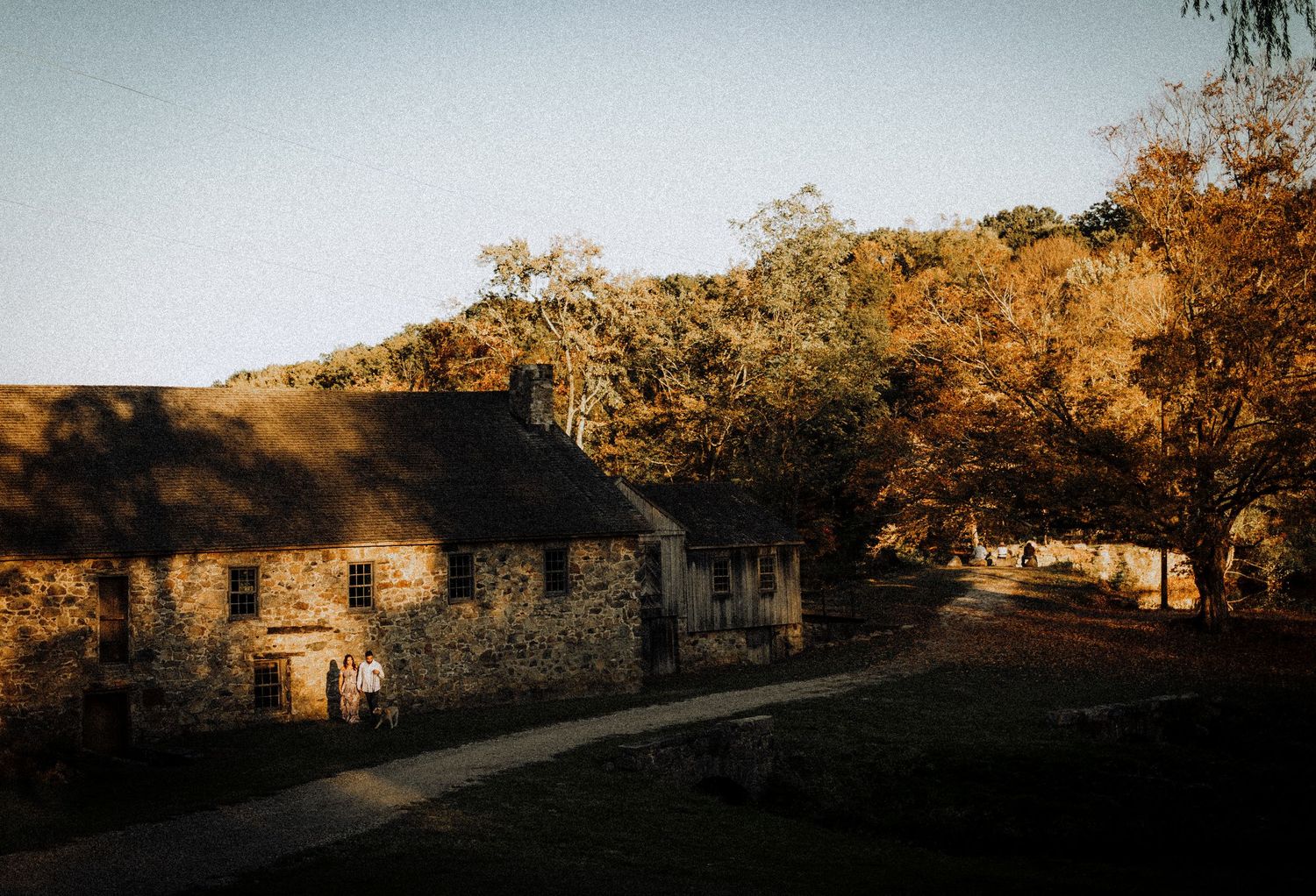 Stone cottages nestled in autumn landscape with warm golden lighting at sunset.