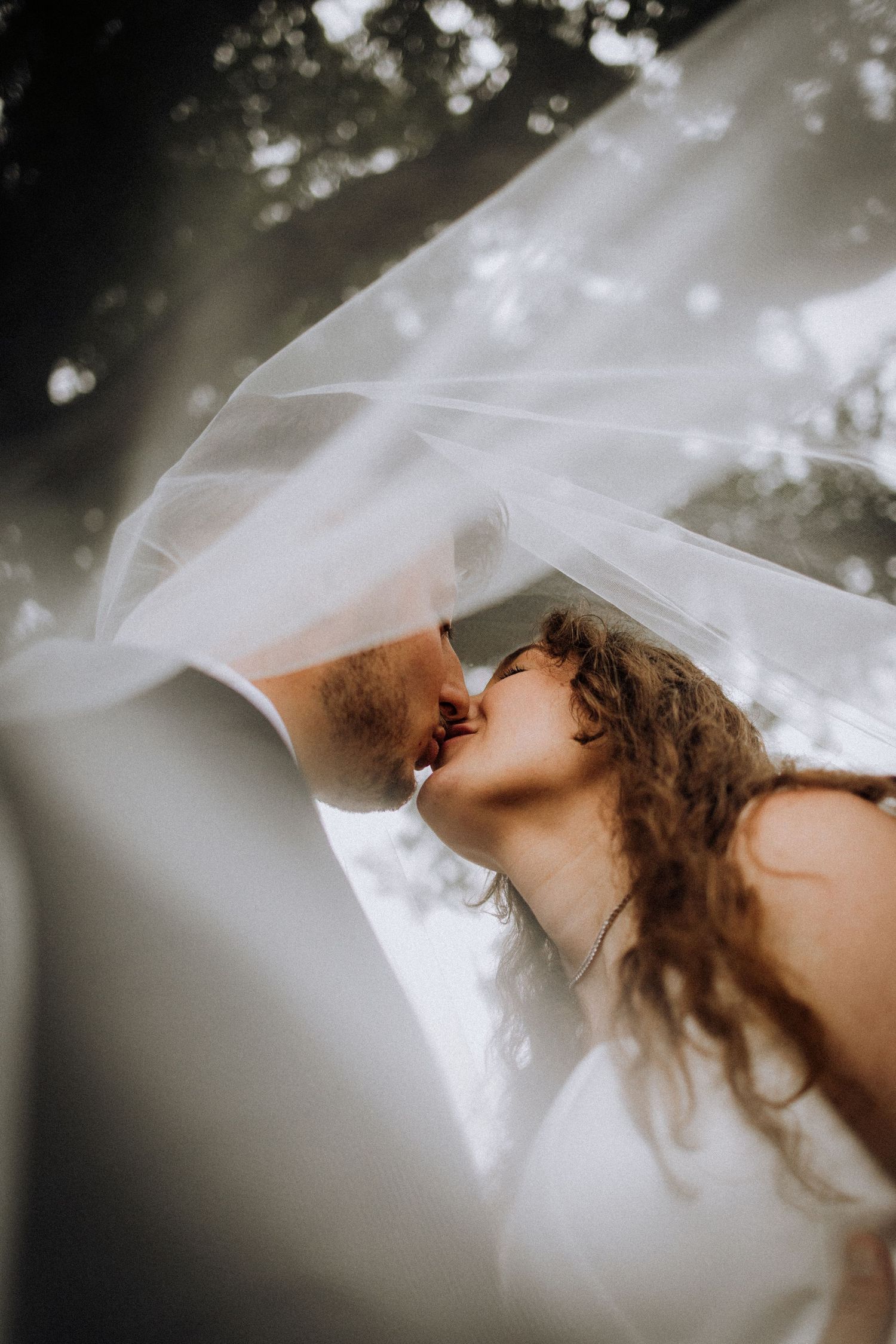 Close-up artistic shots of white wedding veil flowing in natural light.
