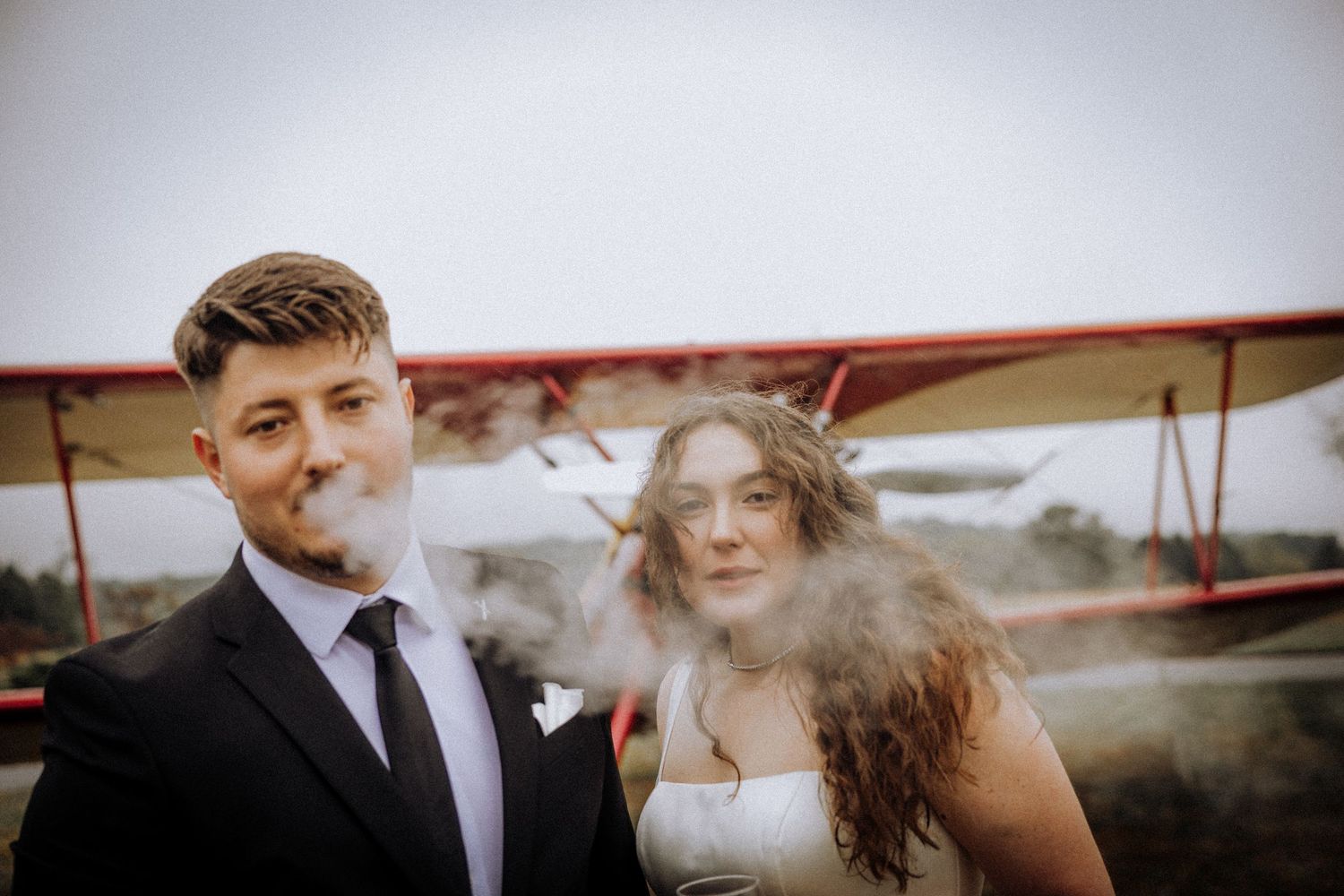 Romantic wedding portrait with classic biplane in background at airfield.