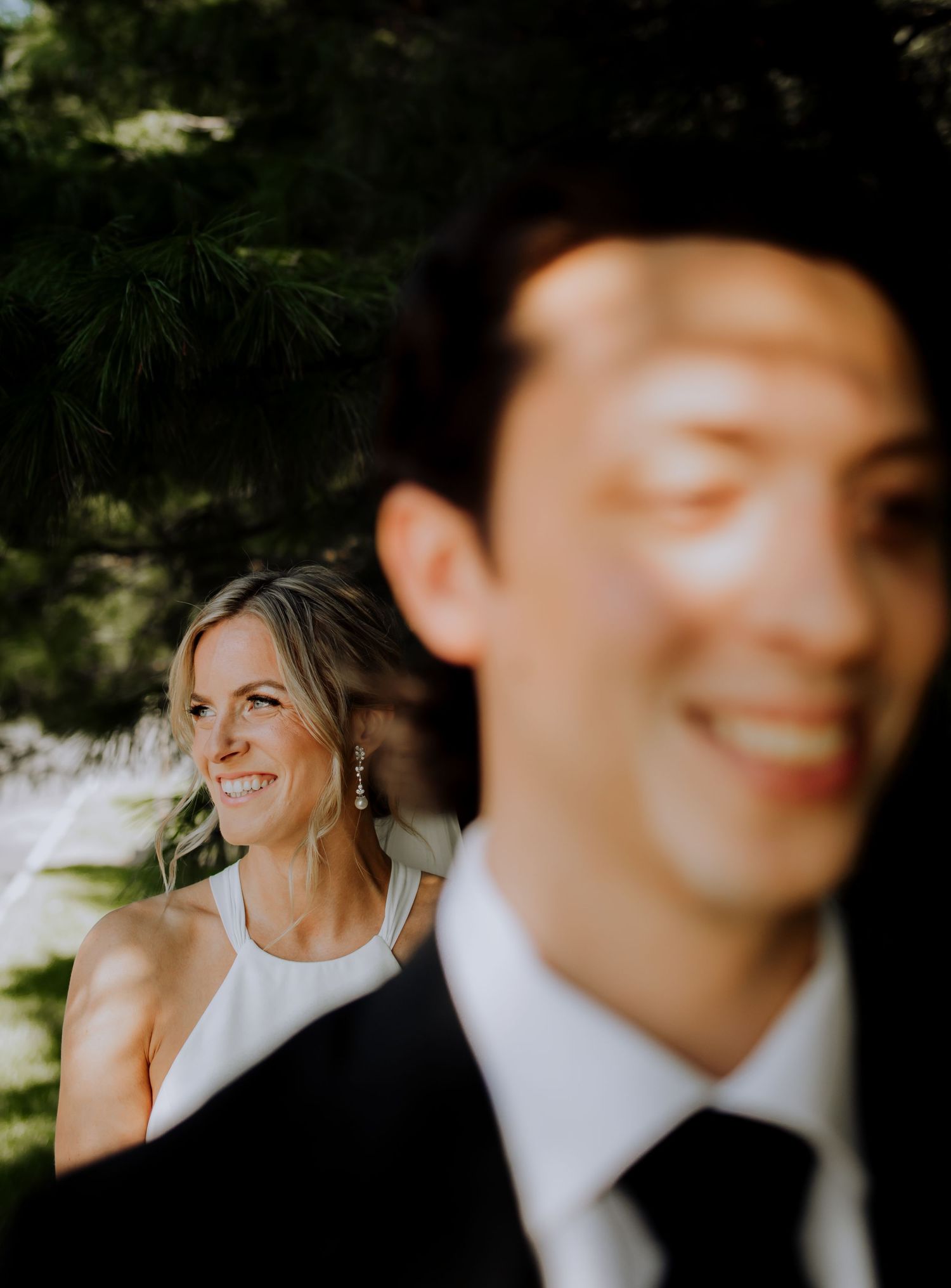 A joyful wedding moment captured outdoors with soft natural lighting and greenery in the background.