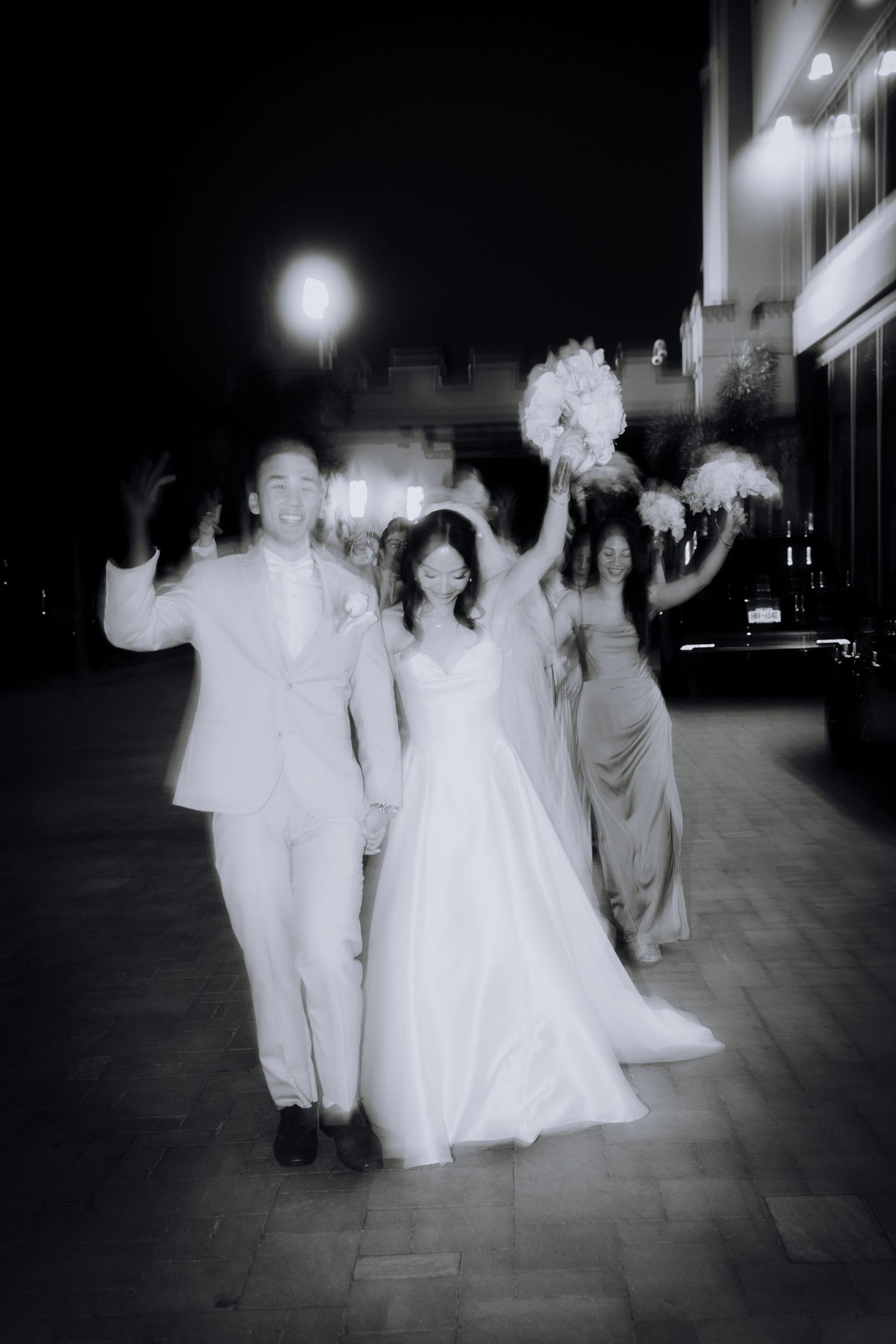 Ethereal black and white wedding procession moving through a dimly lit space.