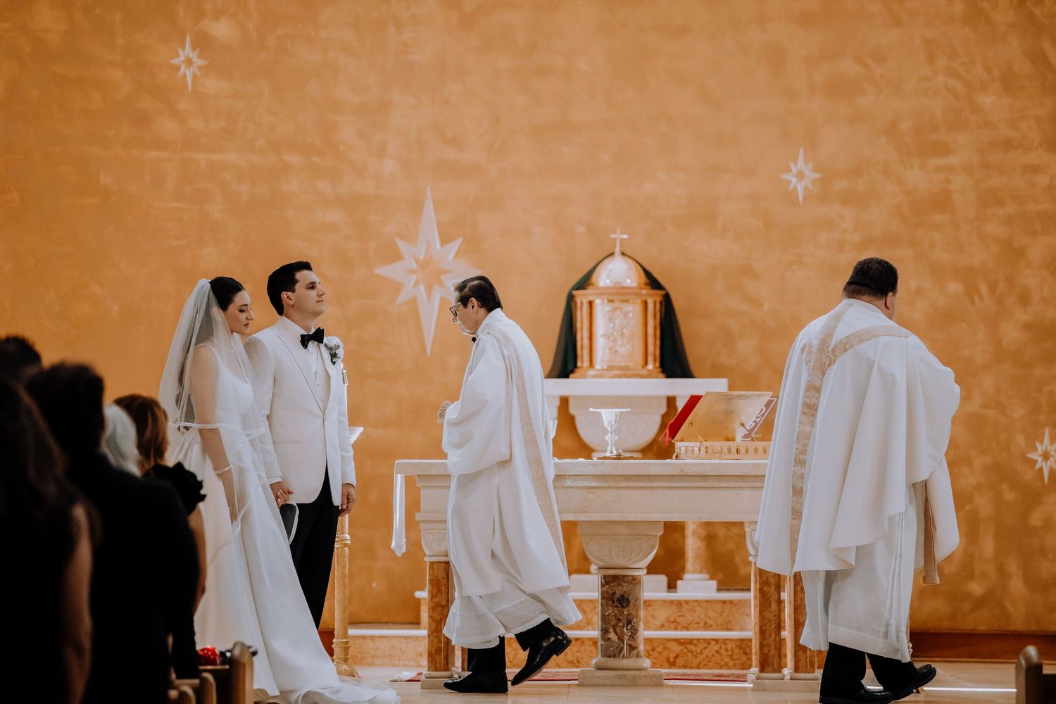Church altar decorated with white linens and crosses for wedding ceremony.