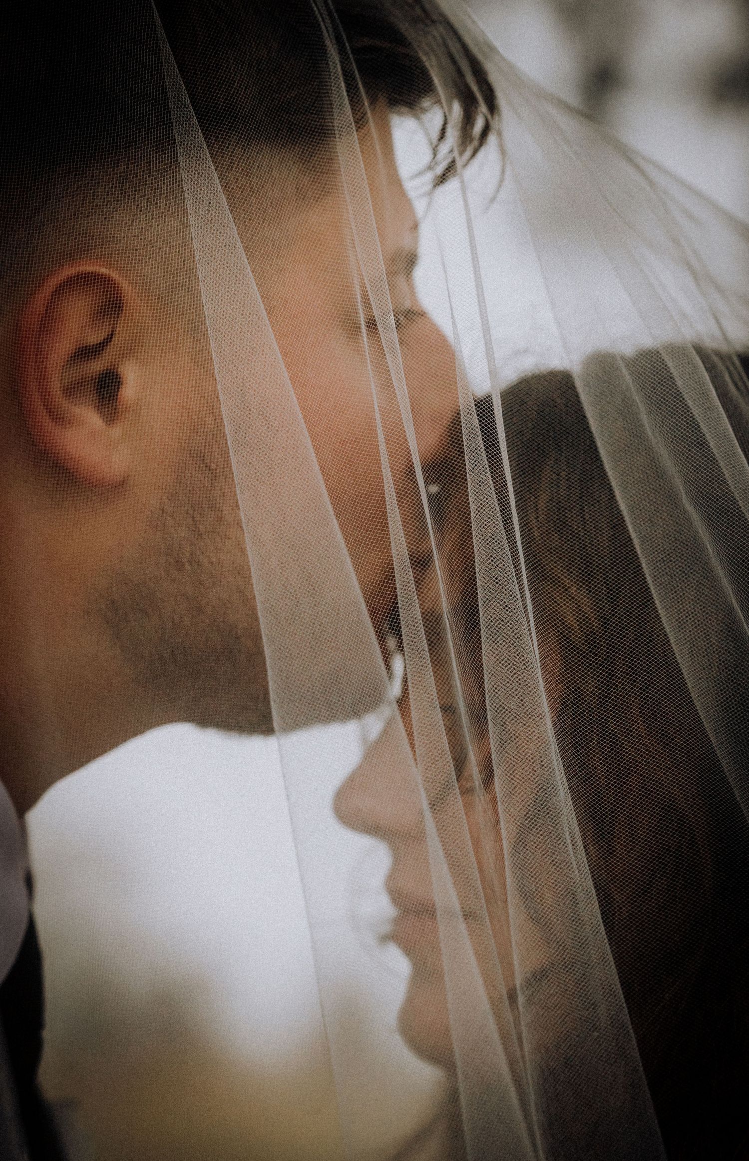 Romantic silhouette through delicate wedding veil in soft focus.