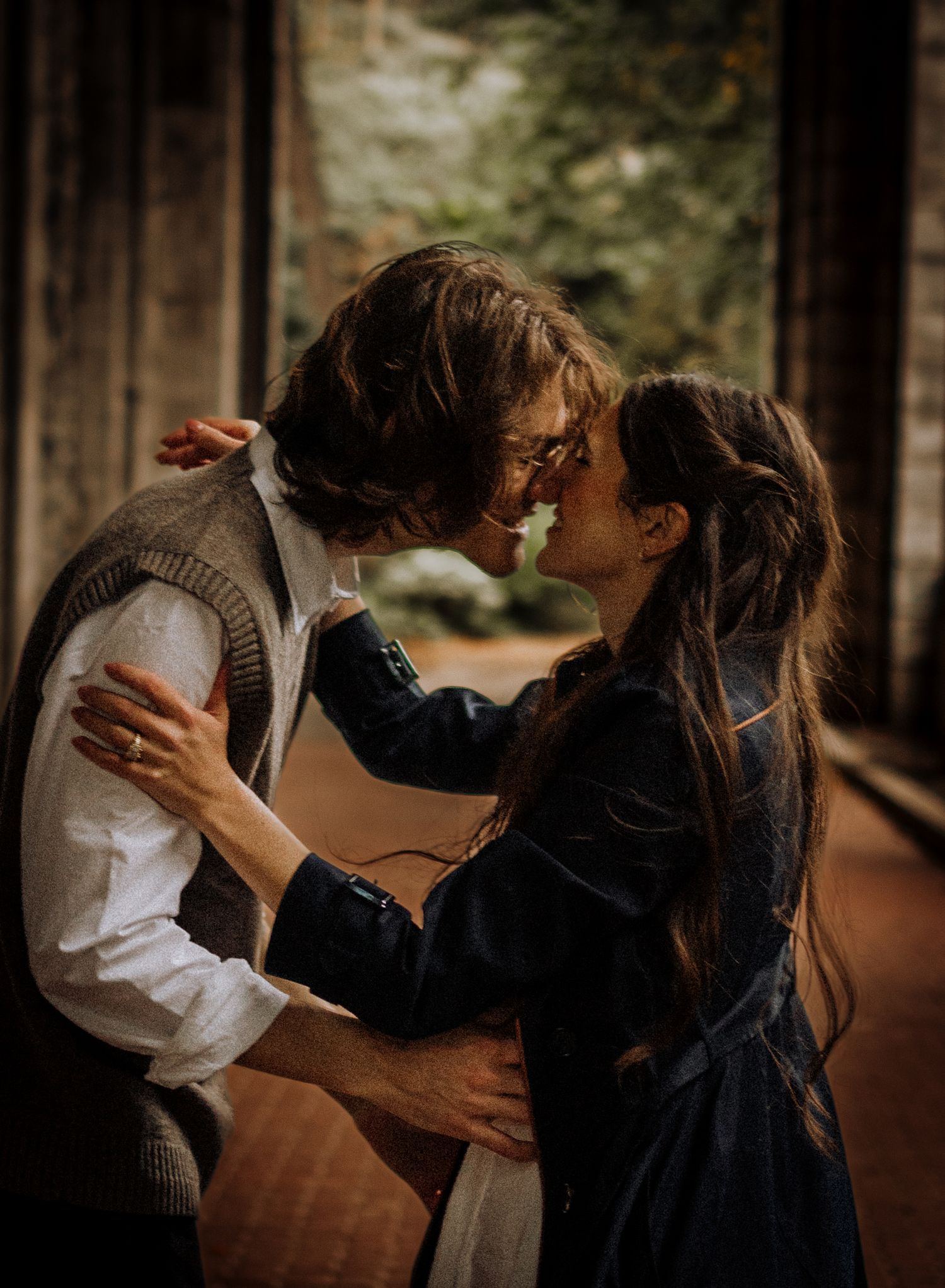 An intimate embrace between a couple in vintage-inspired clothing under stone architecture.