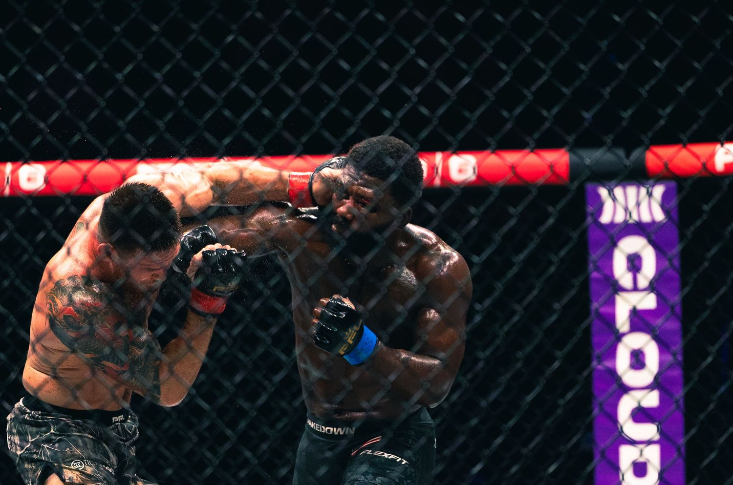 Two MMA fighters exchange punches inside an octagon cage during an intense professional fight.