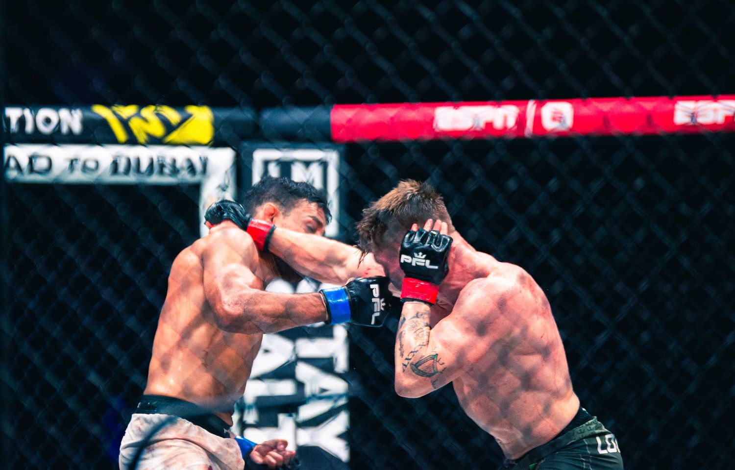 Two MMA fighters exchange punches inside an octagon cage during a professional fight broadcast on ESPN.