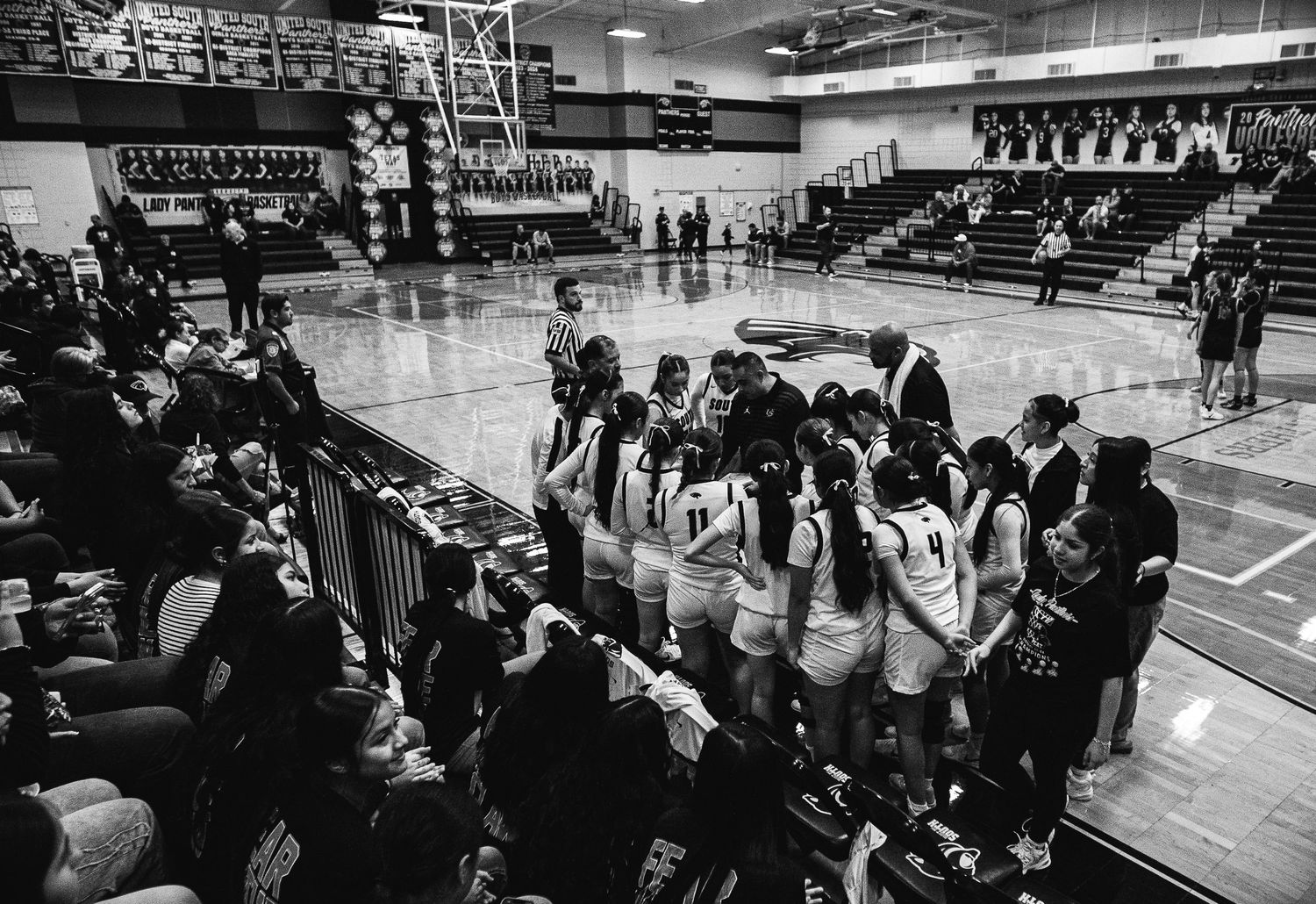 Spectators fill the bleachers at a high school basketball game.