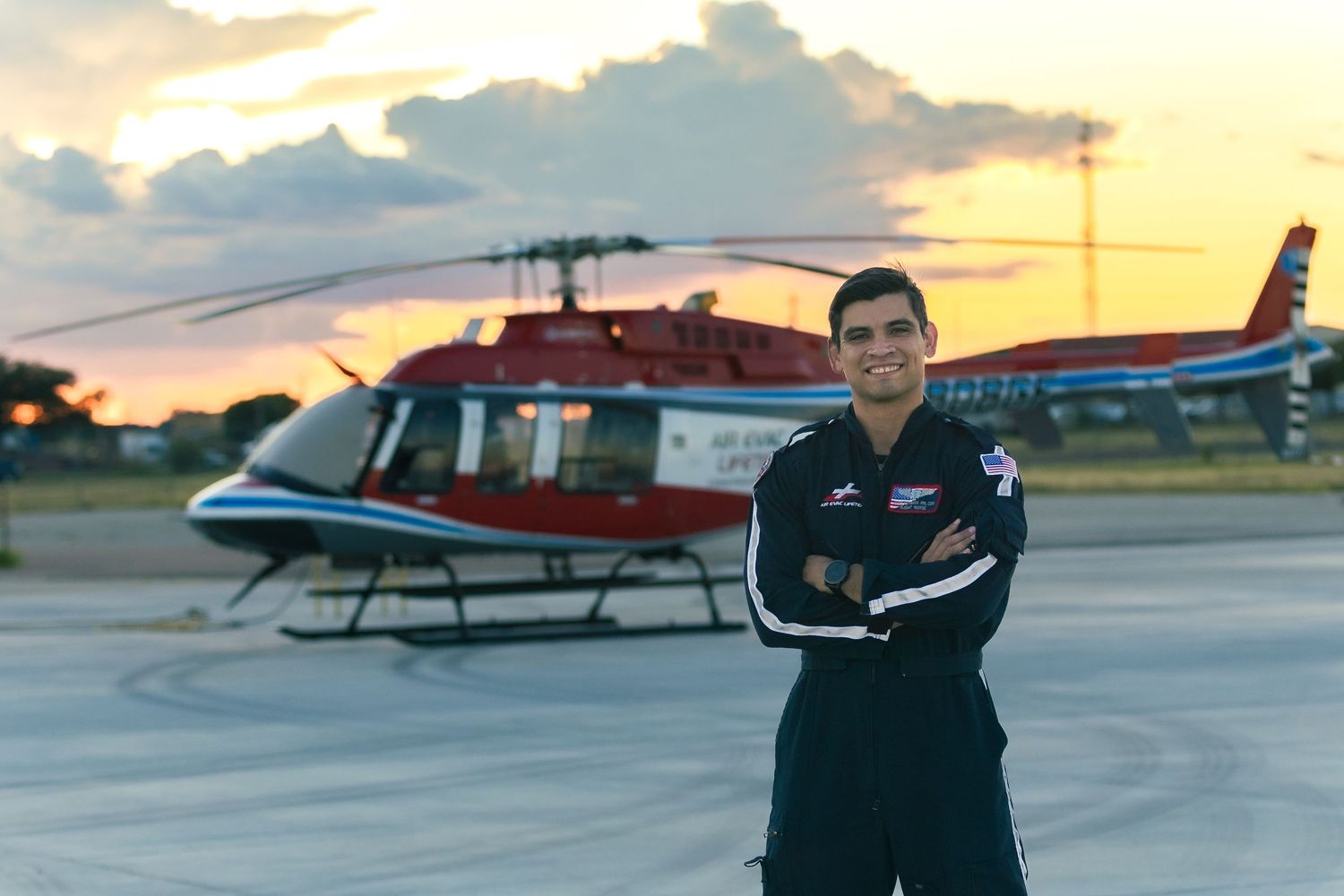 Red and black helicopters parked on tarmac during sunset.