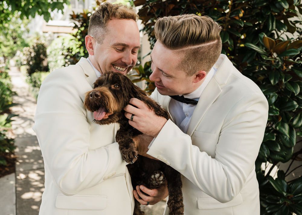 A couple in white outfits share an intimate moment together in a garden setting.