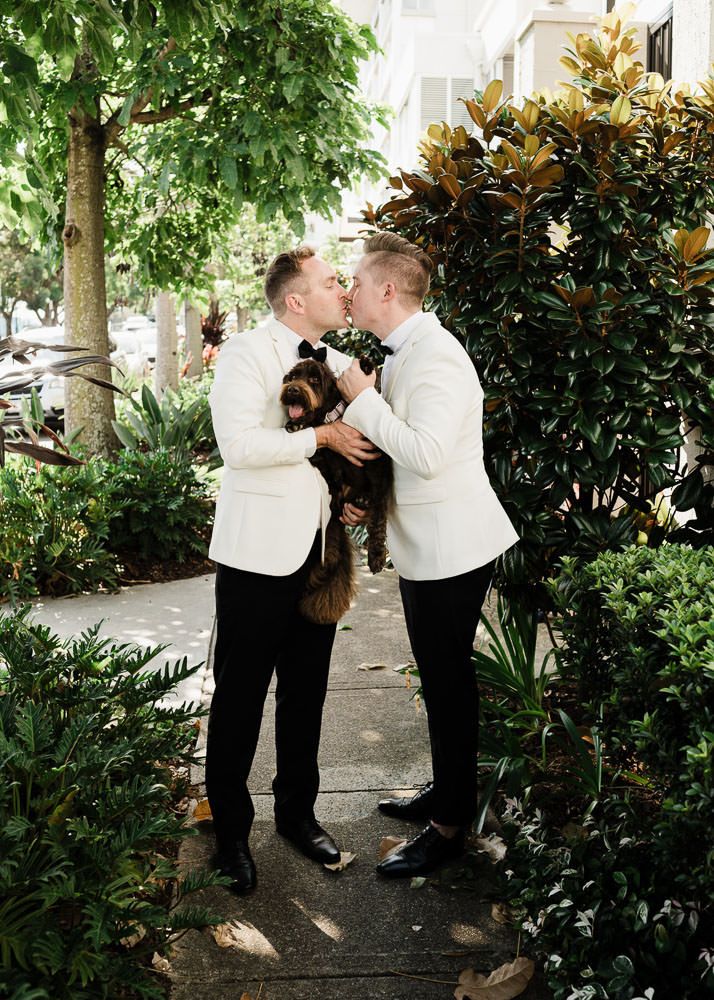 A romantic moment shared between a couple in white shirts surrounded by lush garden greenery.