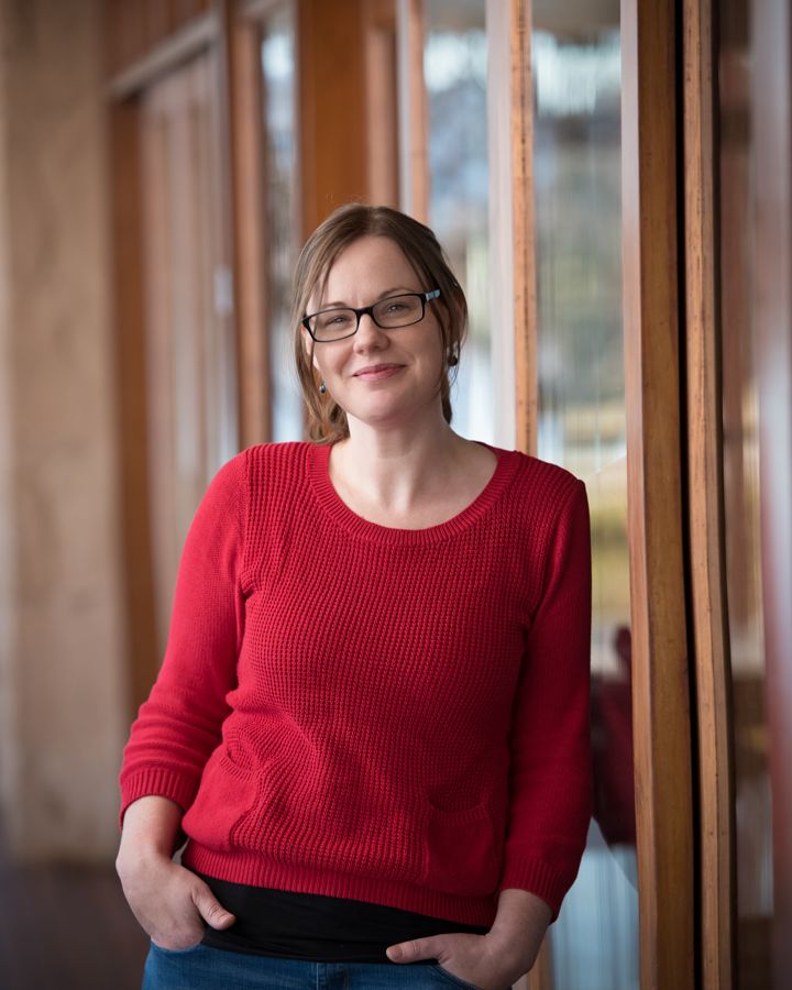Casual portrait series in red sweater by wooden window frames.