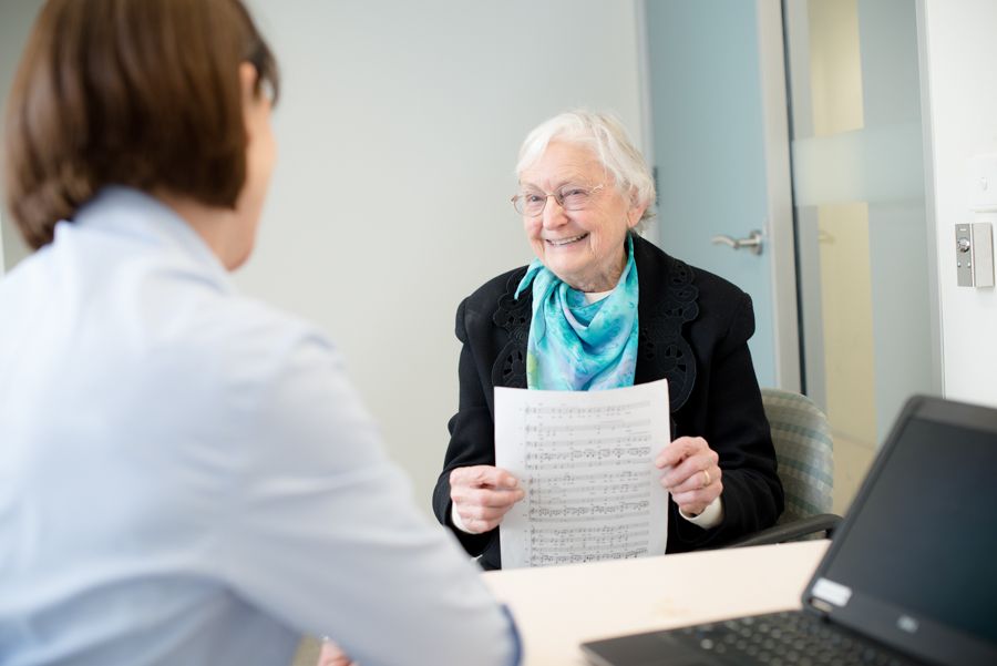 Consultation participants reviewing documents in conference room. Person wearing teal scarf holding sheet music