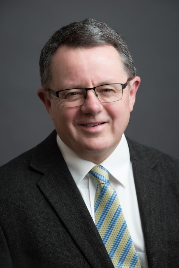 Business portrait series in dark suit and striped tie against grey backdrop.