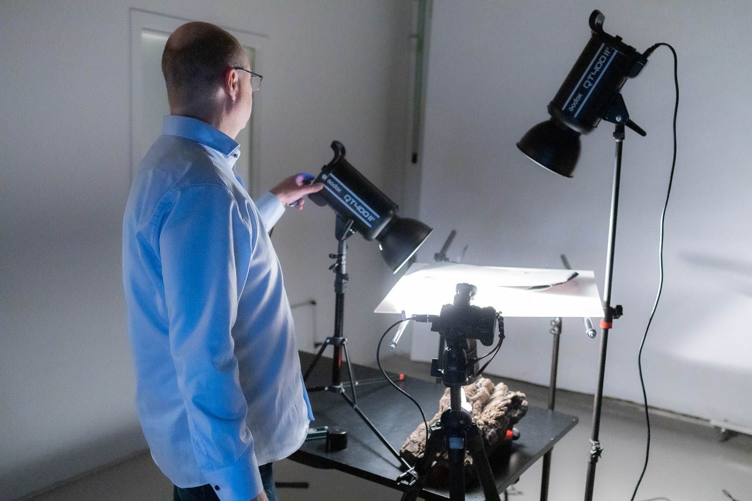 Photographer working with professional lighting equipment in a bright studio setting.