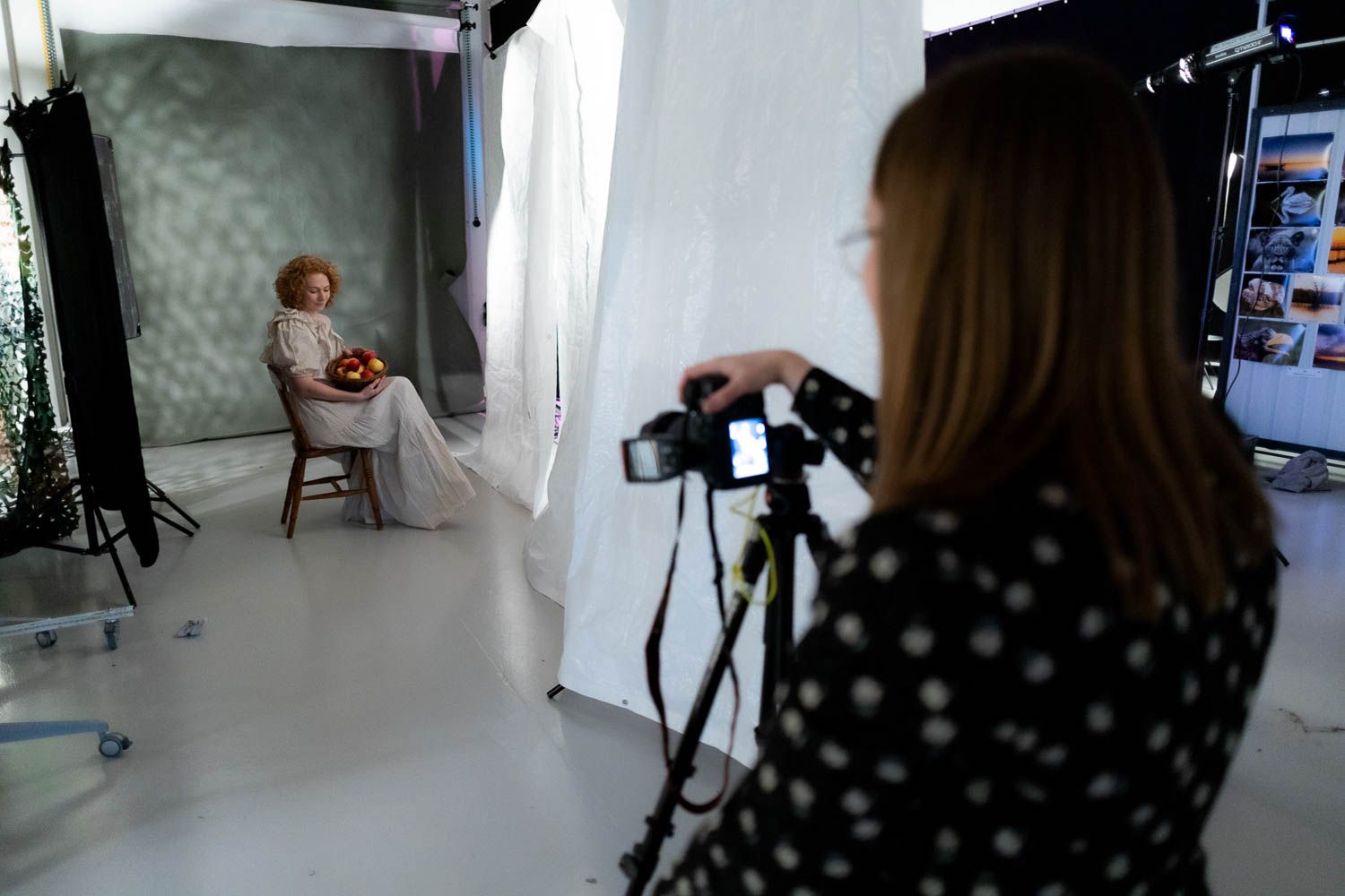 Photography studio setup showing camera equipment and lighting against white backdrop.