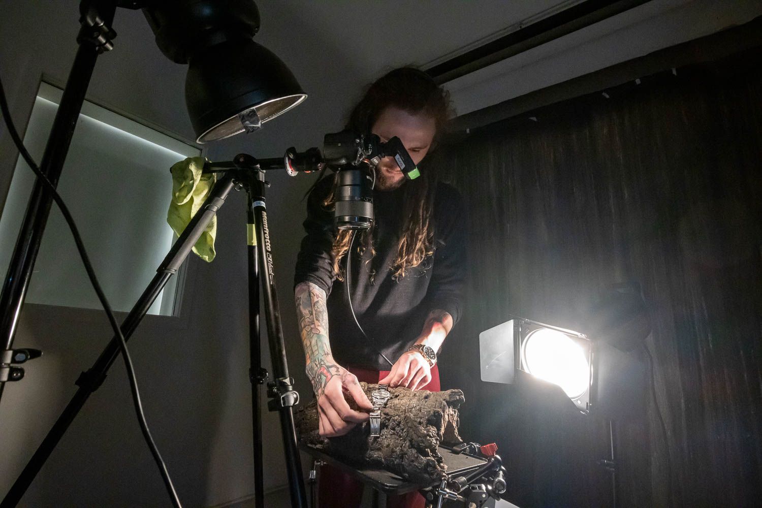 Dark studio setup with dramatic lighting and camera equipment visible.