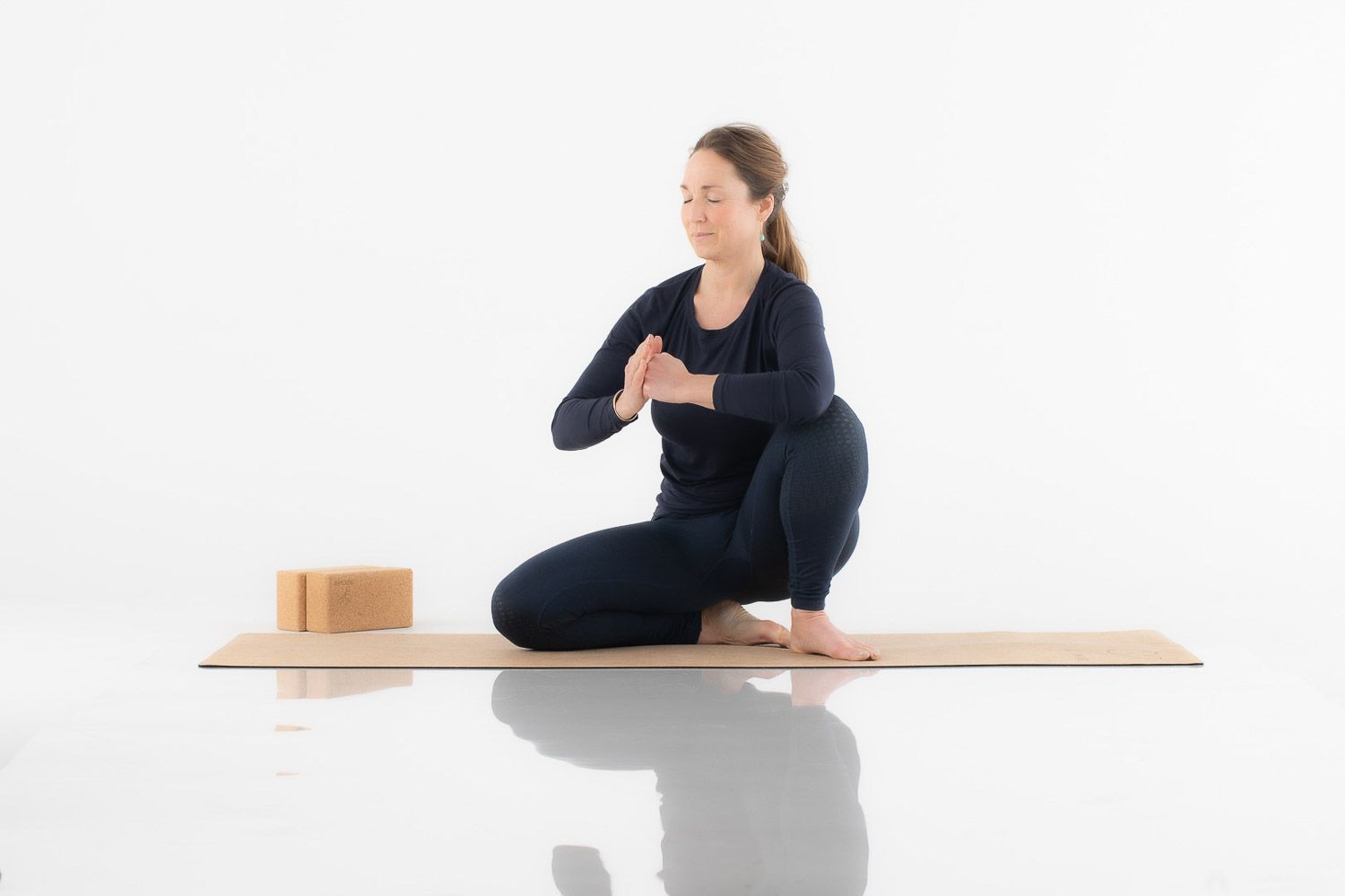 Demonstration of various yoga positions on a wooden platform against white backdrop.