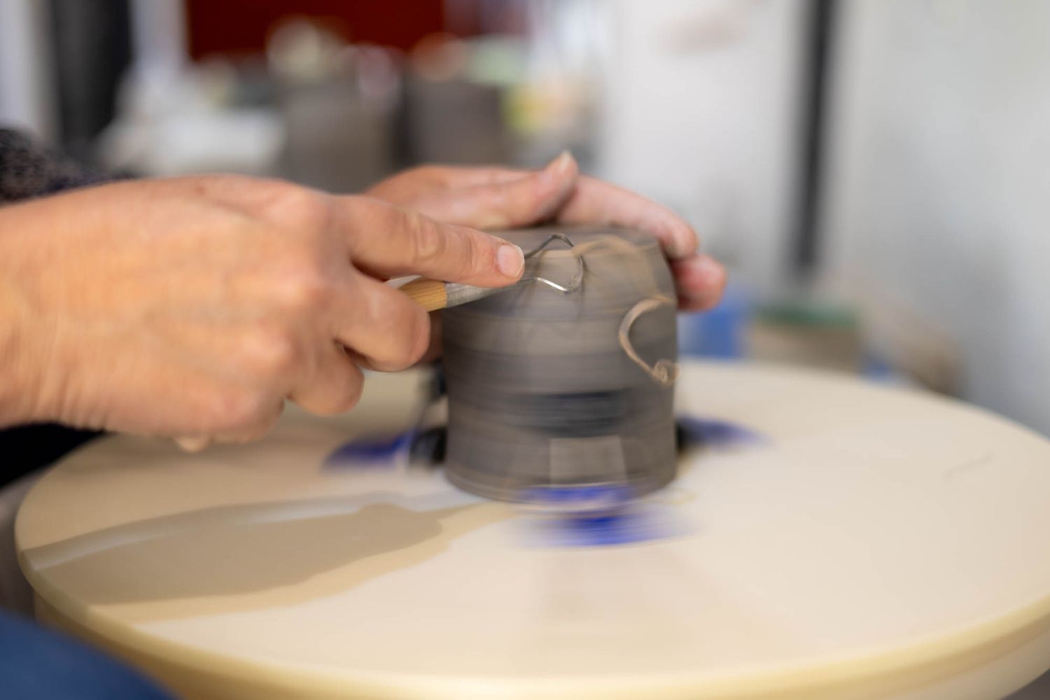 Hands shaping clay on a pottery wheel with focused precision.