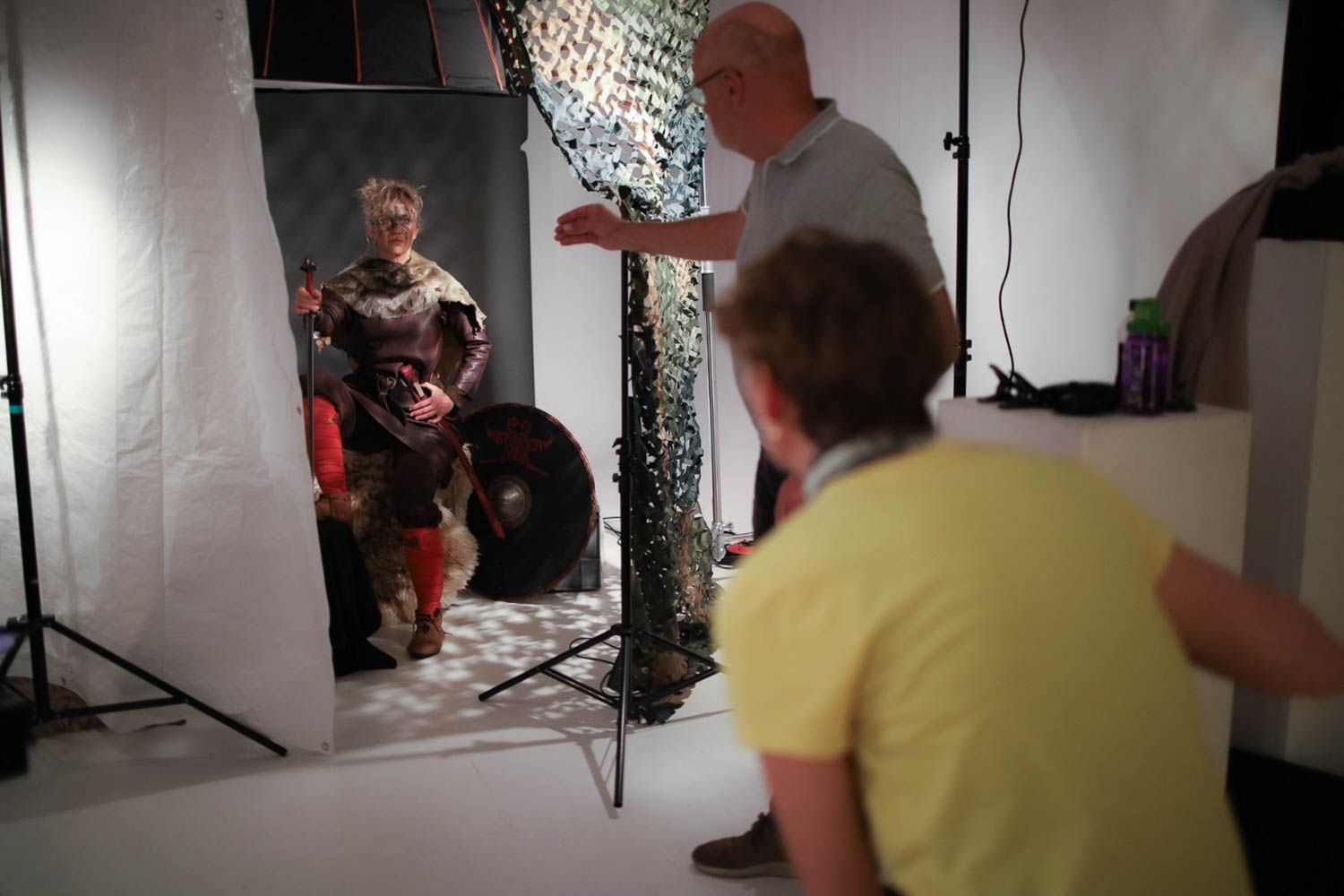 Studio photo shoot setup with lighting equipment and colorful backdrop visible.