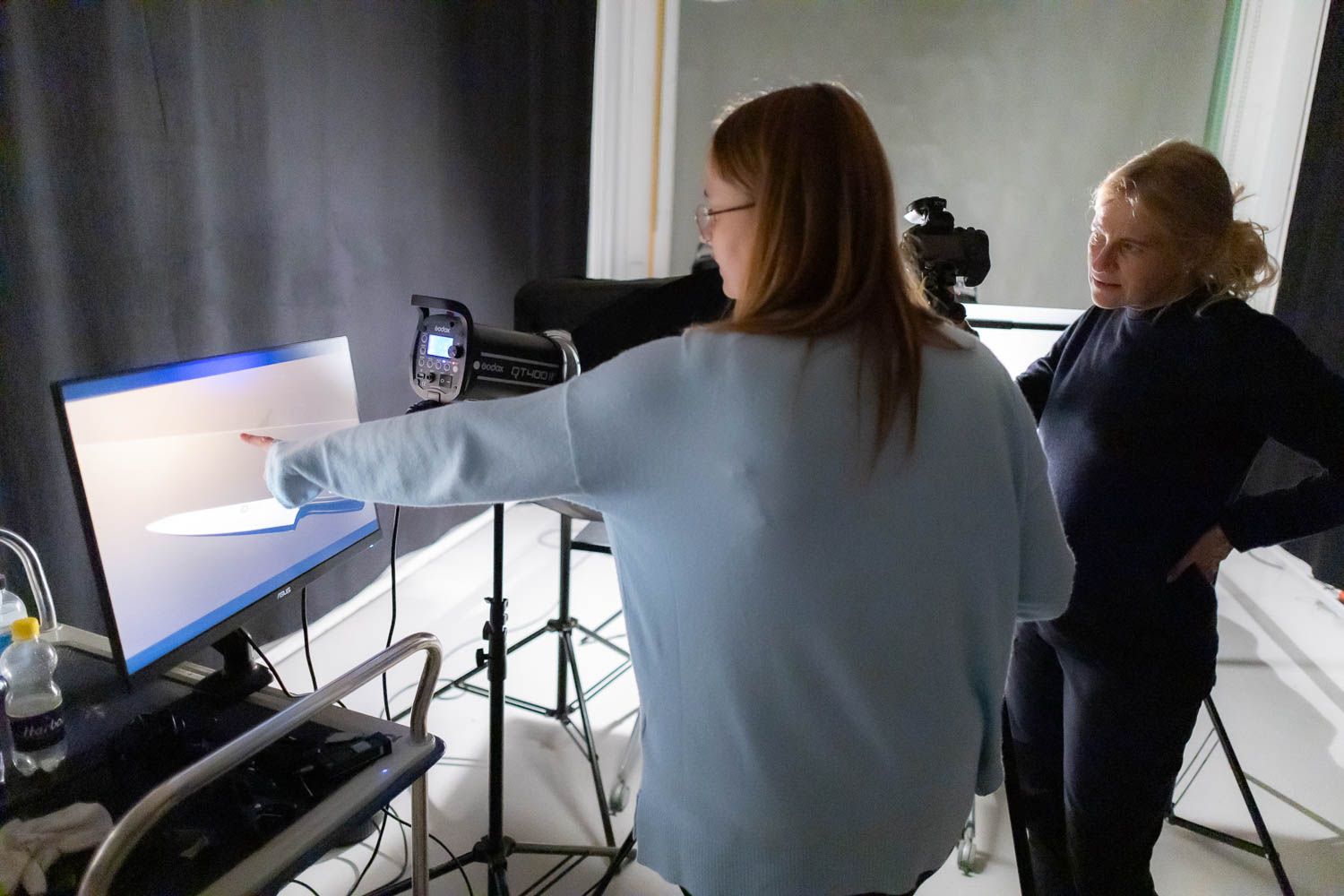 Photography session in progress with lighting equipment and reflectors visible.