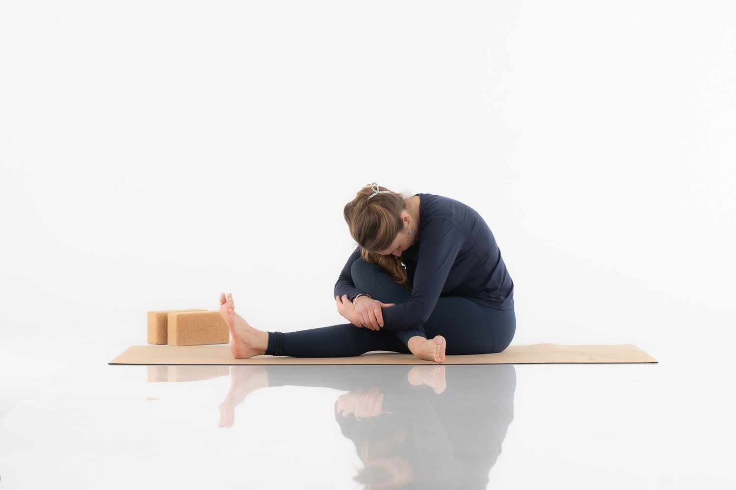 Person in navy clothing performing stretching exercises on wooden platform.
