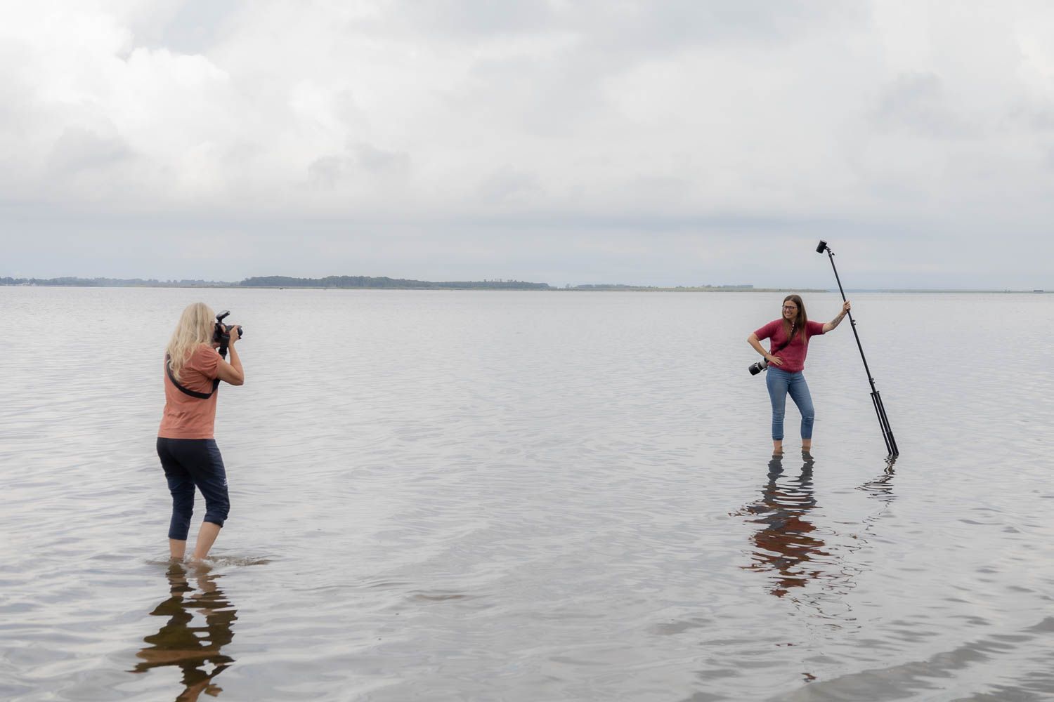Photography team working on a shoot in shallow water under cloudy skies.