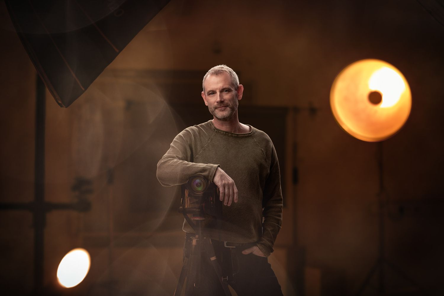 Moody portrait with dramatic lighting showing figure in casual wear against warm background glow.