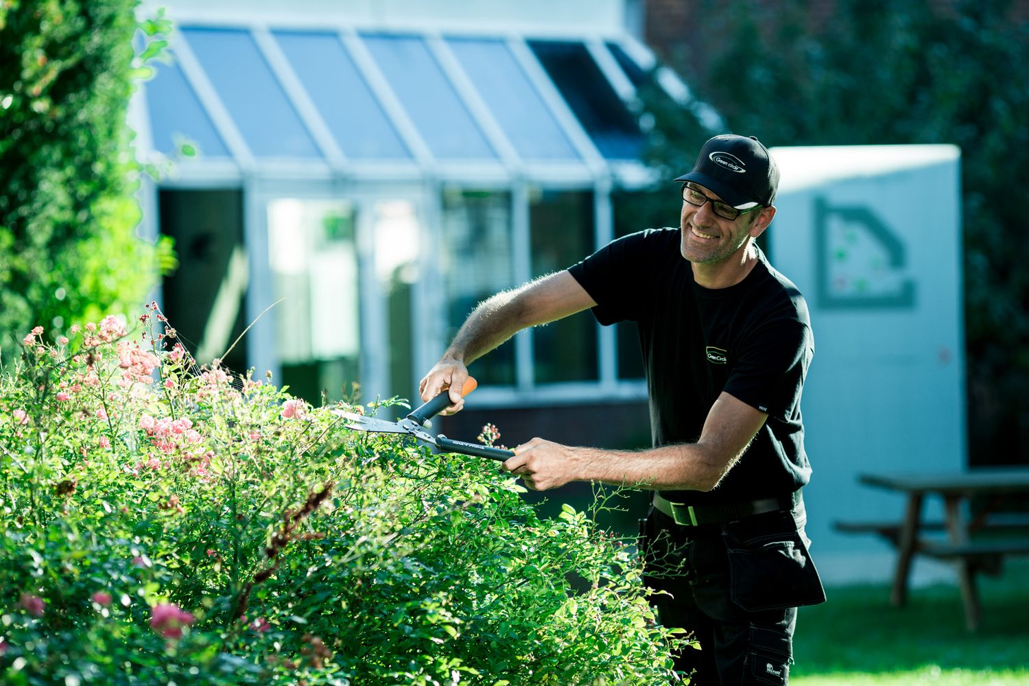 Professional pest control worker spraying treatment around residential property.