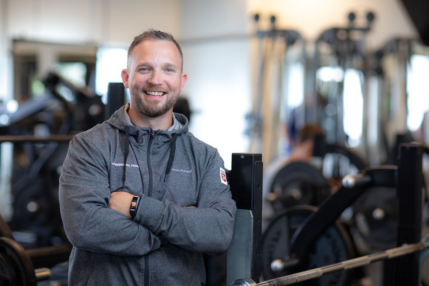 Fitness professional in dark clothing standing in modern gym facility.