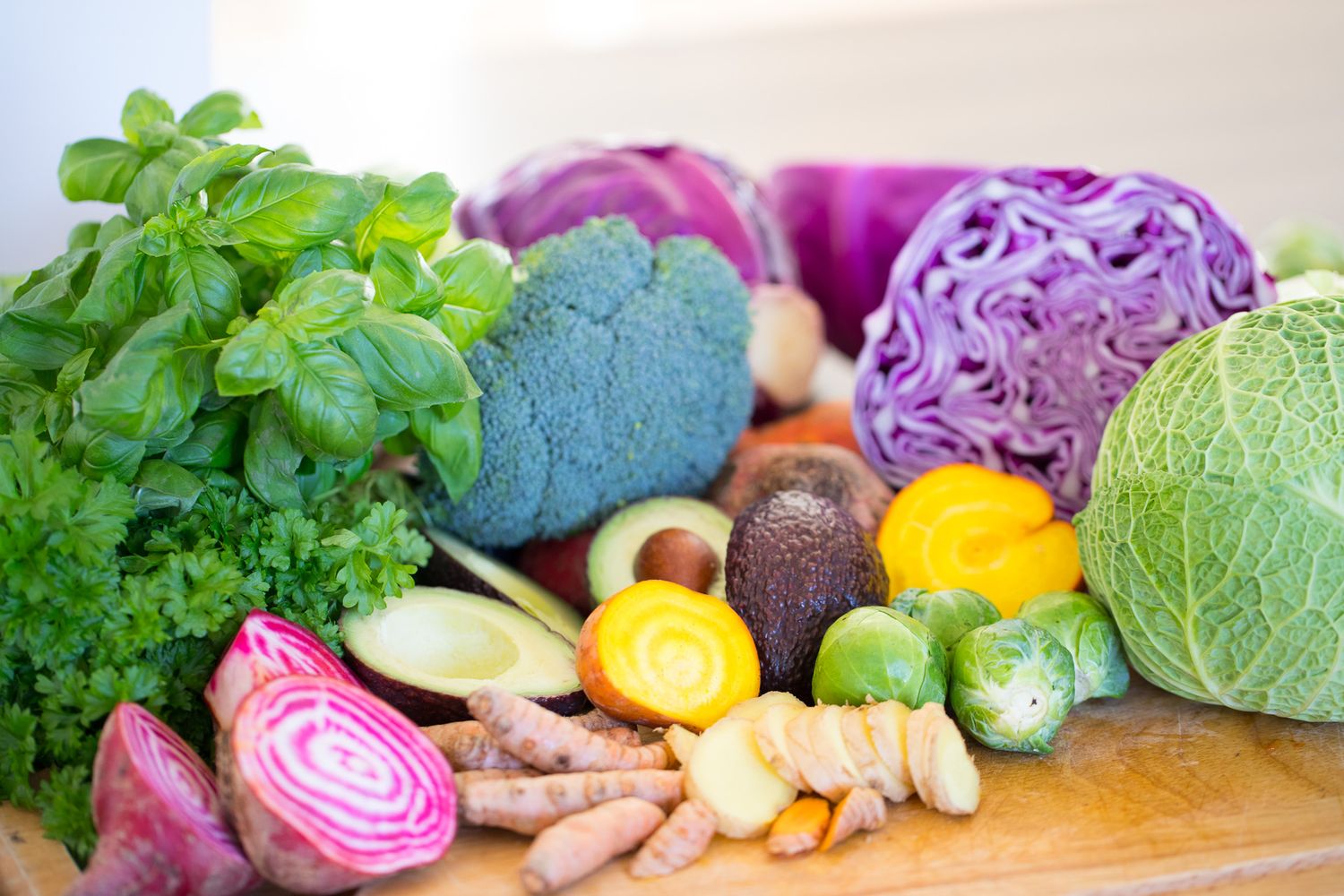 Colorful array of fresh vegetables including cabbage, beets, and herbs arranged on a counter.