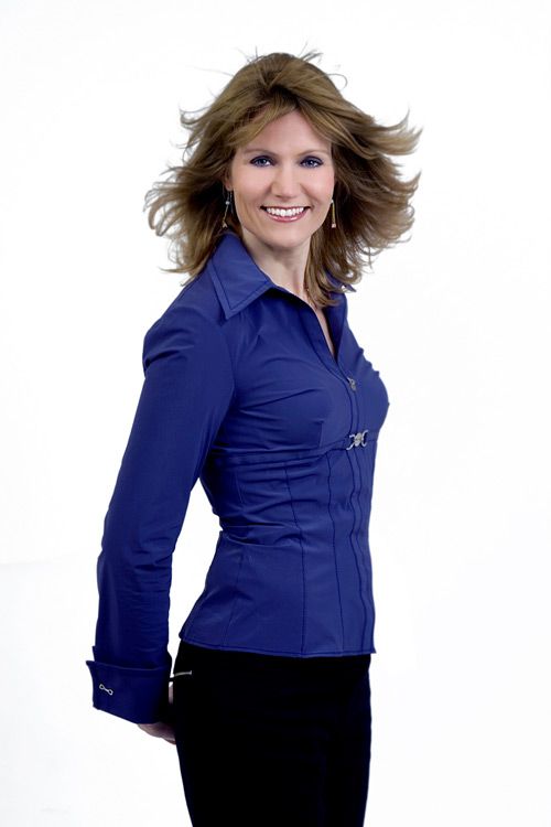 Professional portrait against white background wearing a fitted blue button-up shirt.