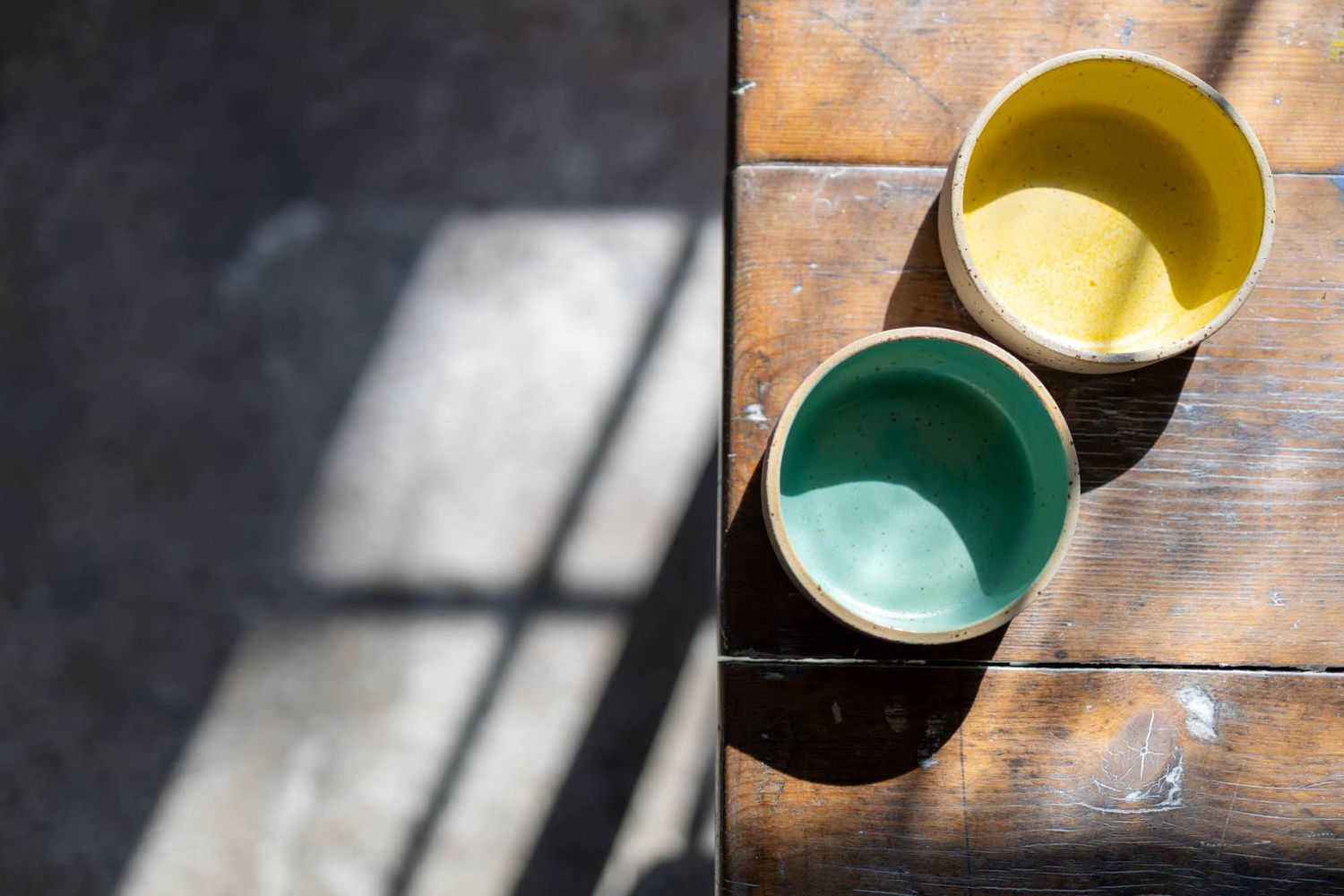 Overhead view of colorful ceramic bowls on a weathered wooden surface.