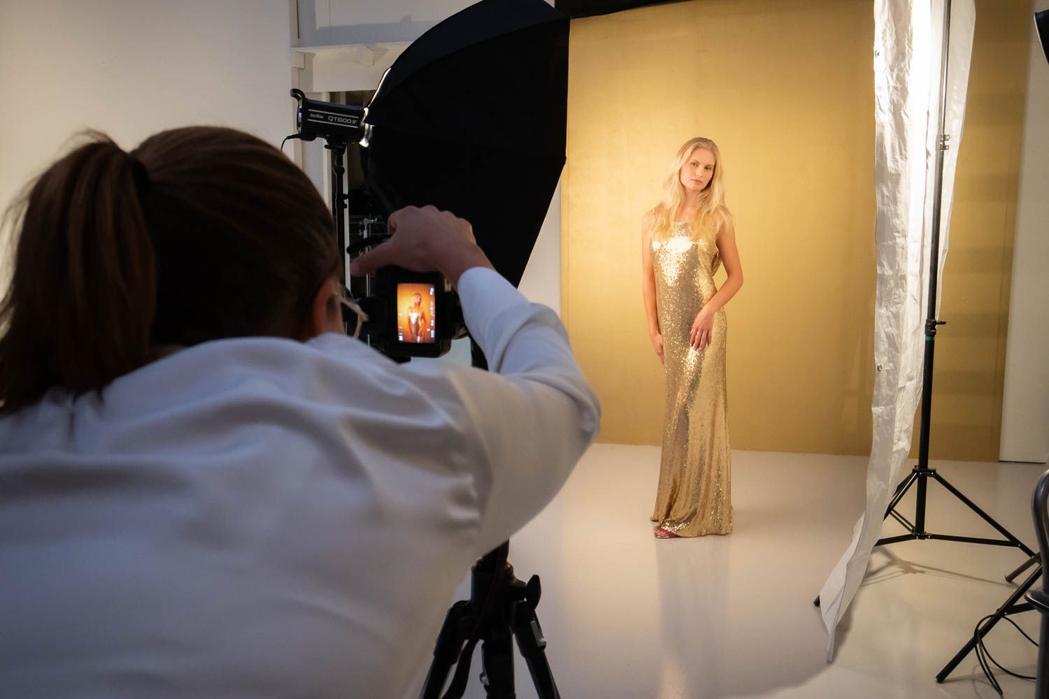 Fashion photography session in progress with warm lighting and professional studio equipment.