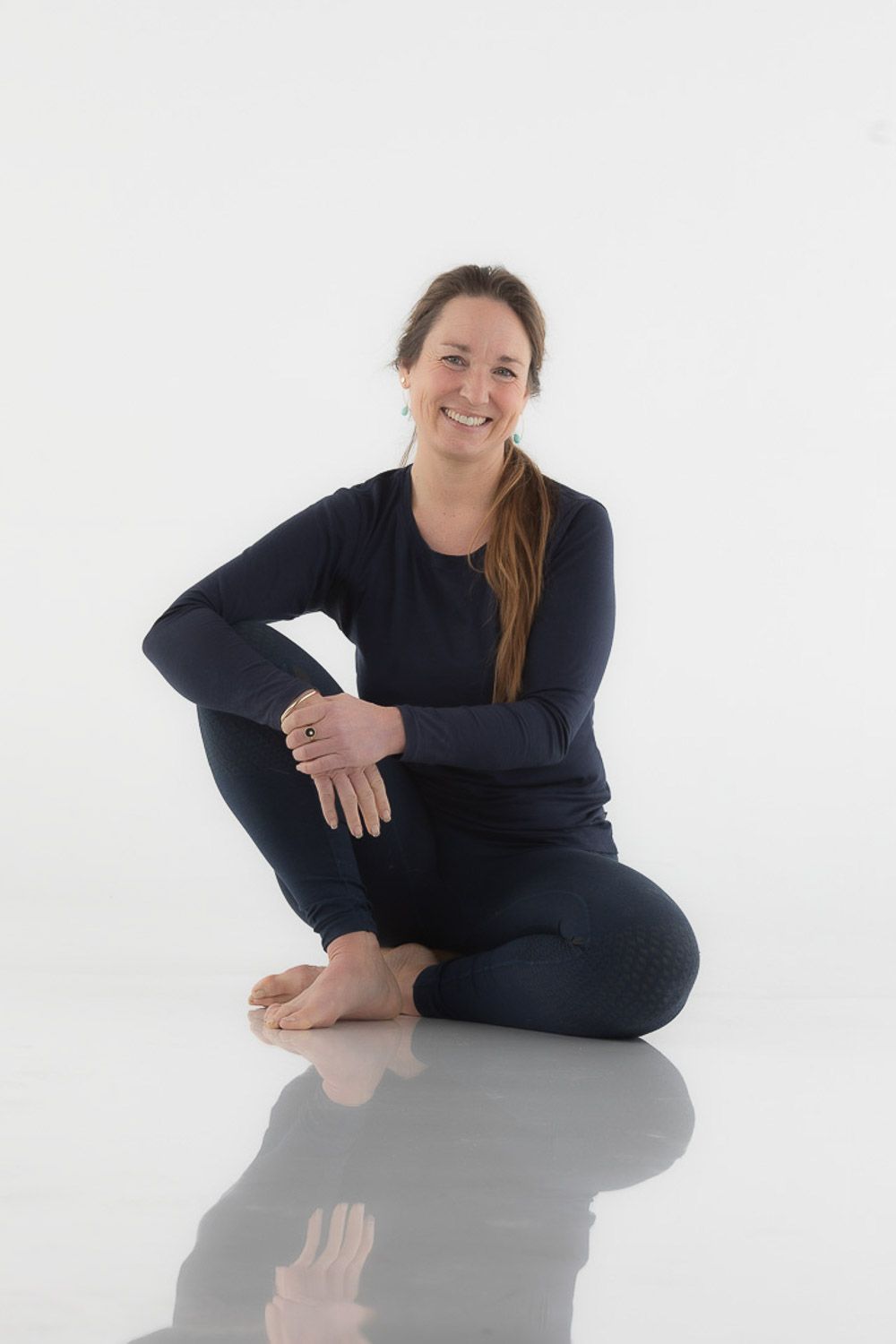 Casual portrait of someone sitting comfortably in navy clothing on reflective floor.