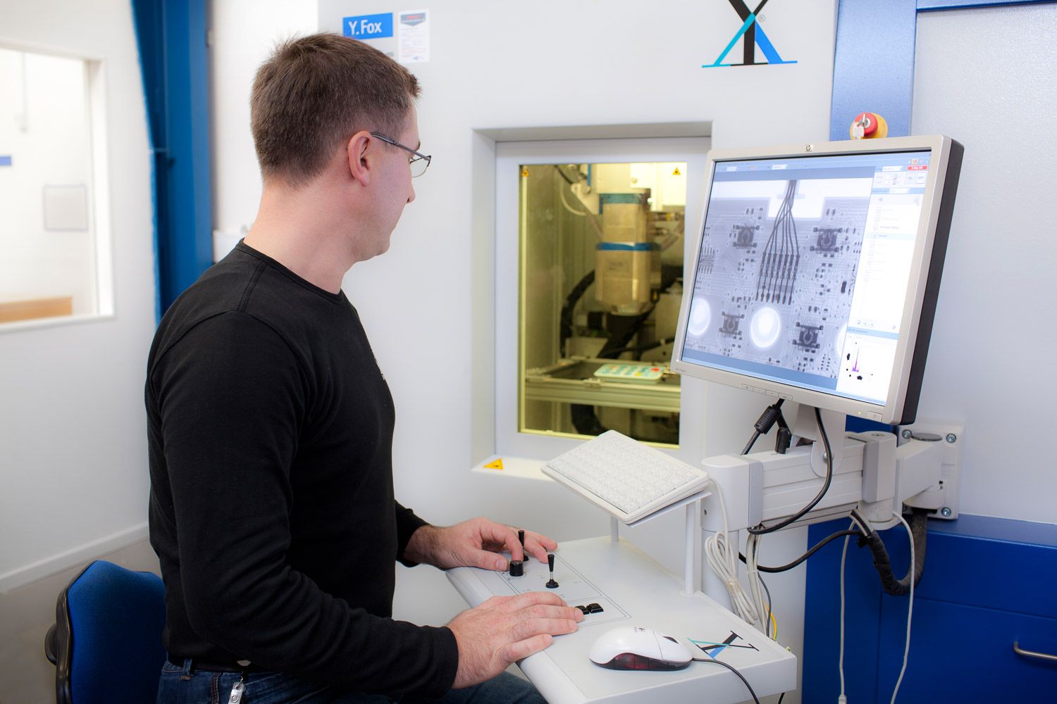 Scientist operating computer system while monitoring laboratory equipment.