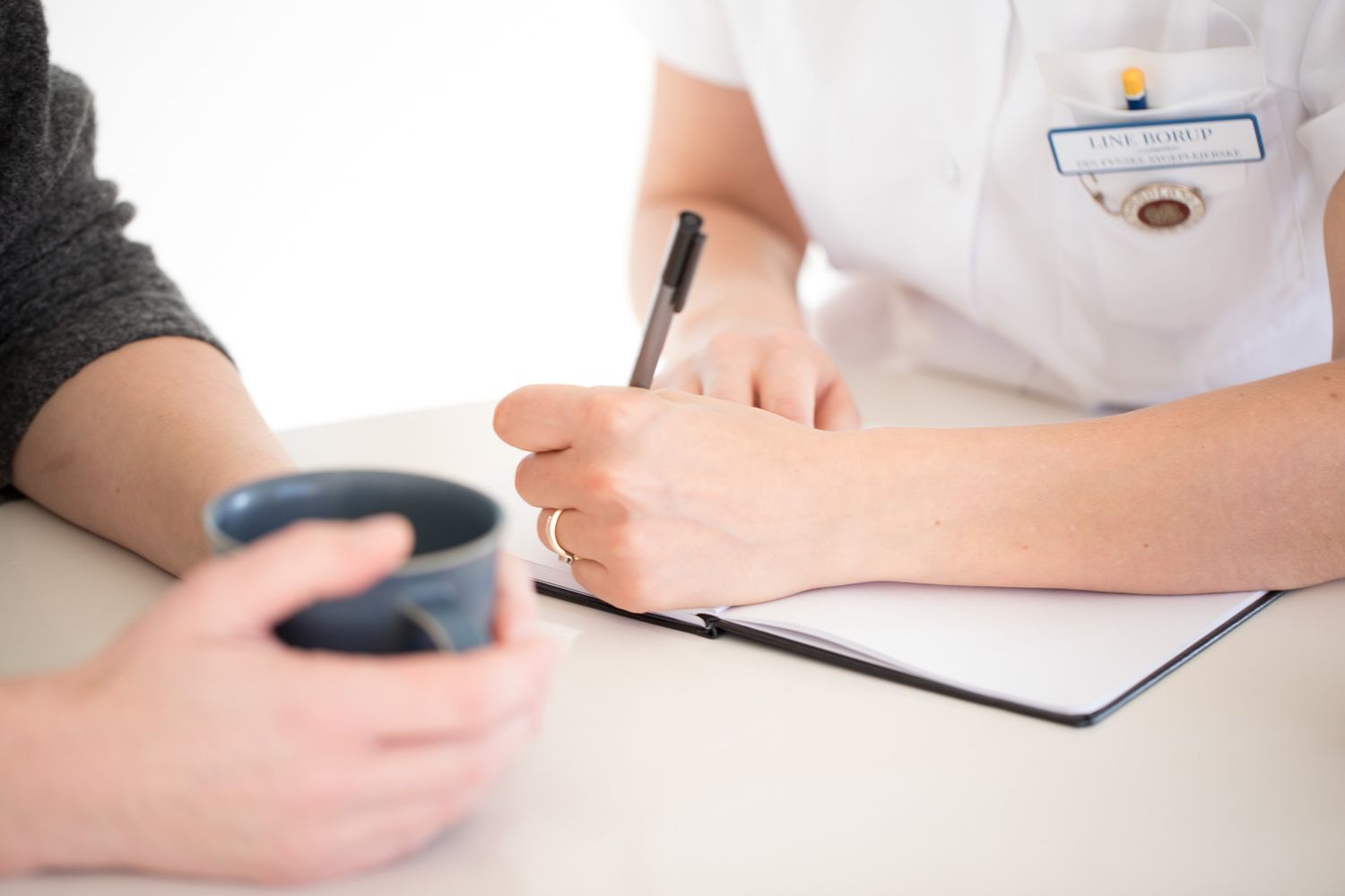 Medical consultation desk with paperwork and professional interaction.