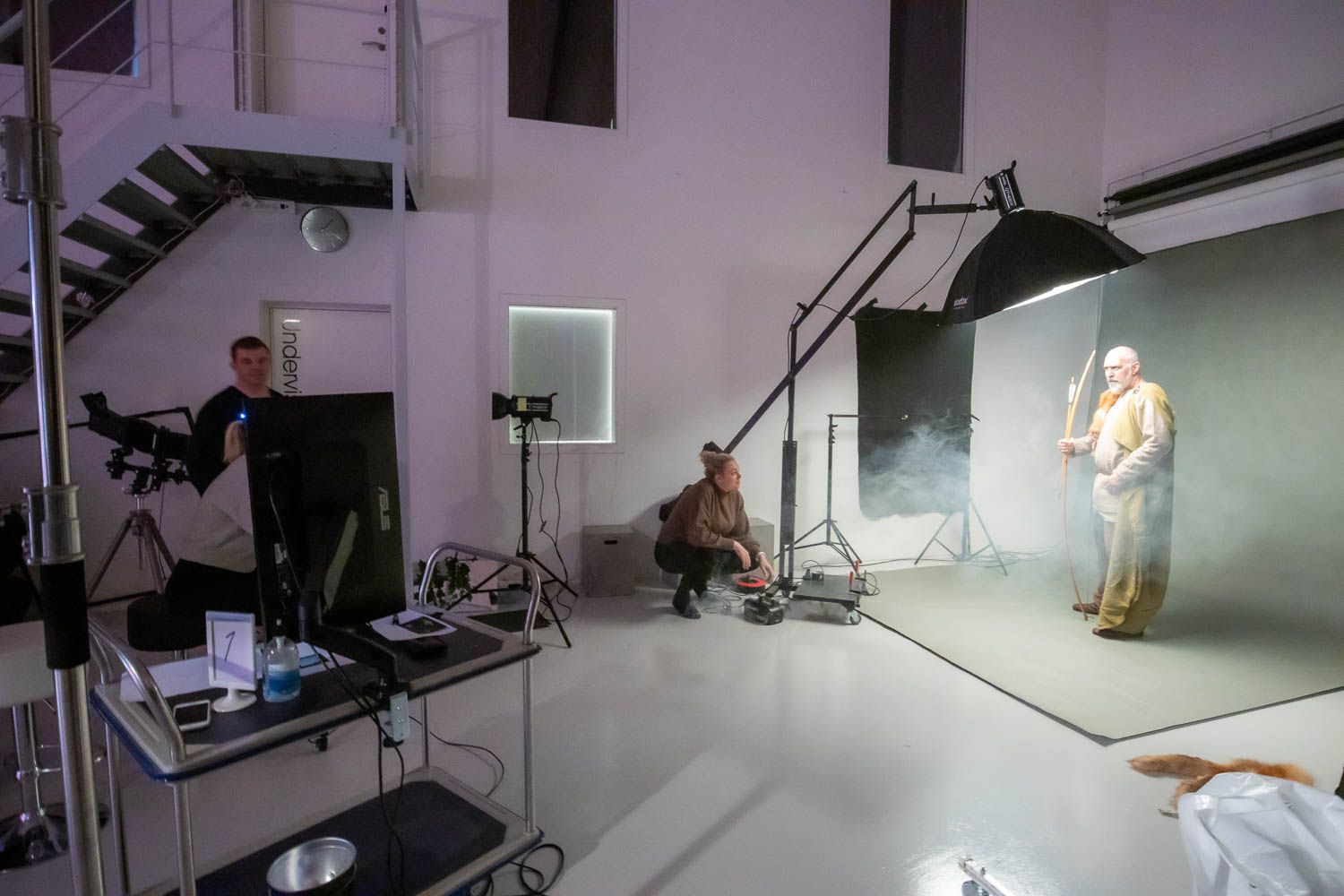 Professional photography studio setup with lighting equipment and backdrop during a shoot.