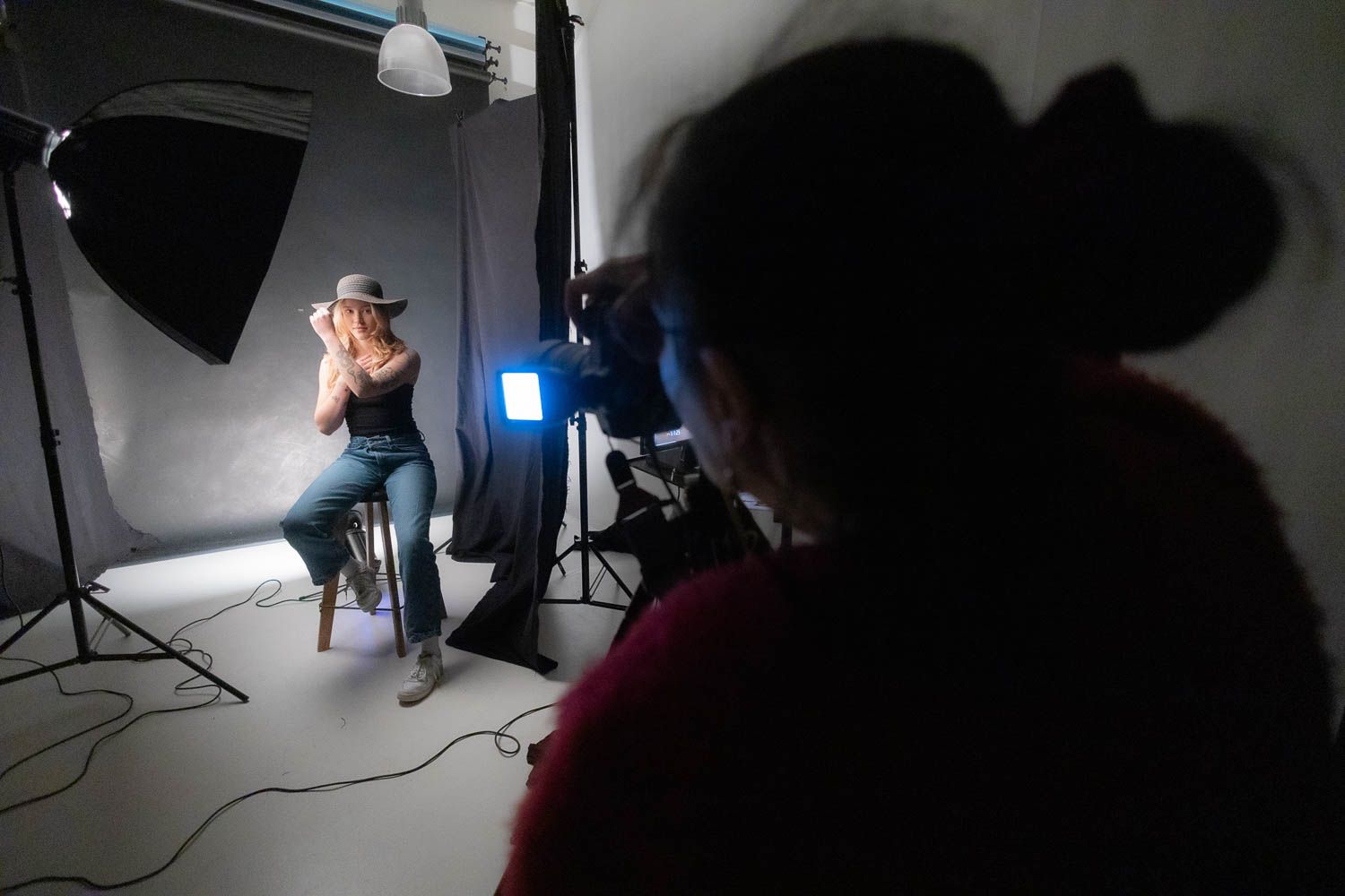 Dark studio environment with blue lighting and photography equipment silhouettes.