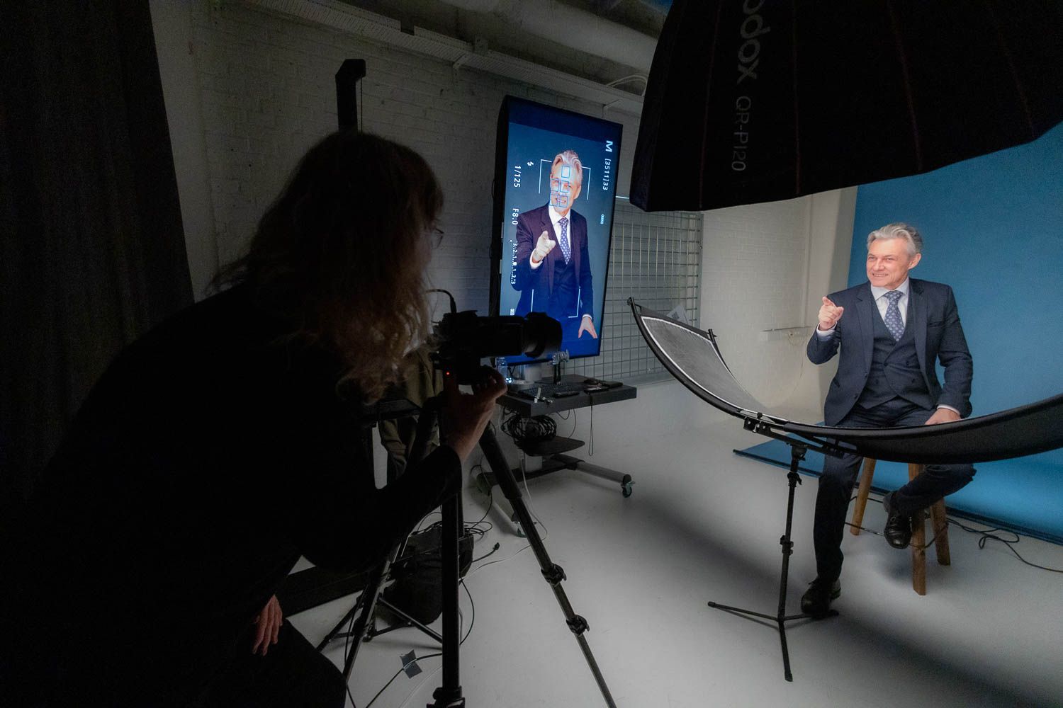 Professional studio photography setup with multiple lights and blue backdrop visible.