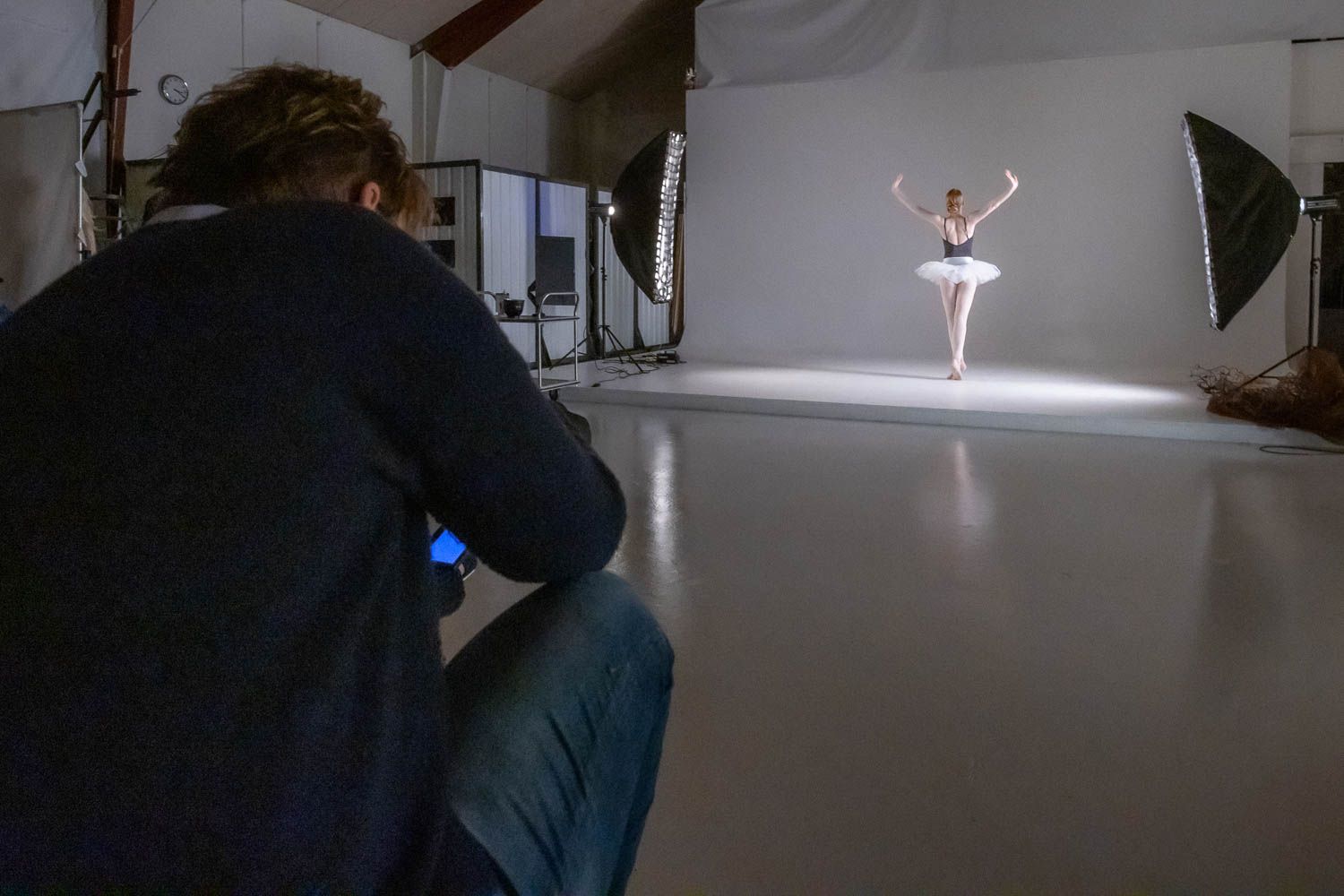 Professional photo shoot setup with dramatic lighting and white backdrop visible.