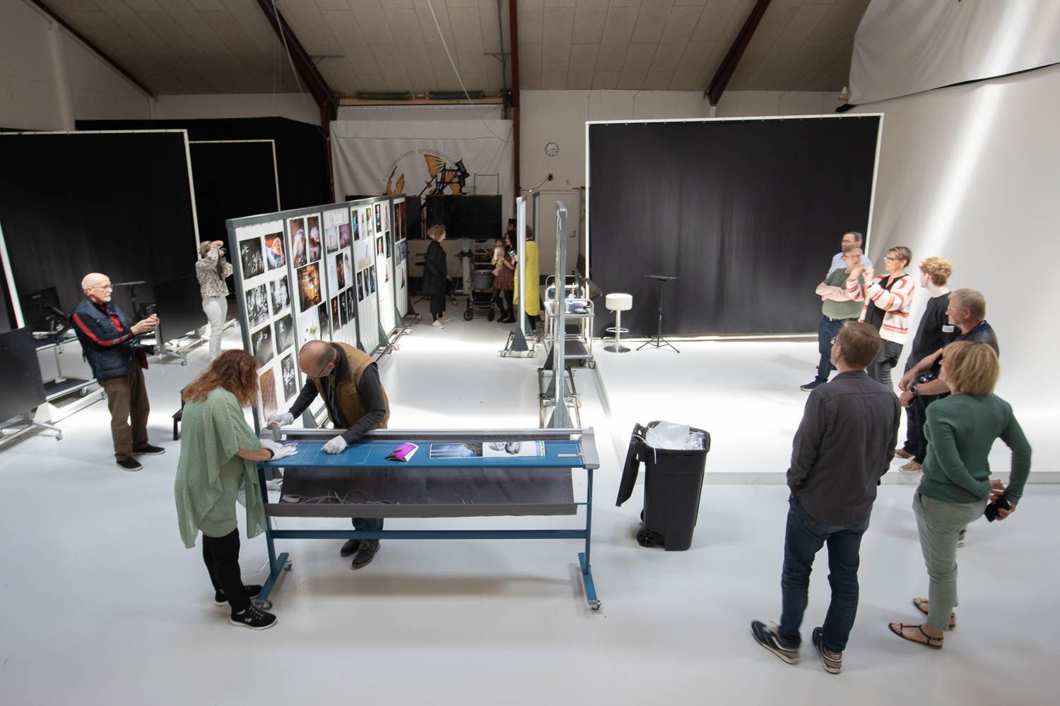Wide view of an art gallery space with people viewing mounted photographs.