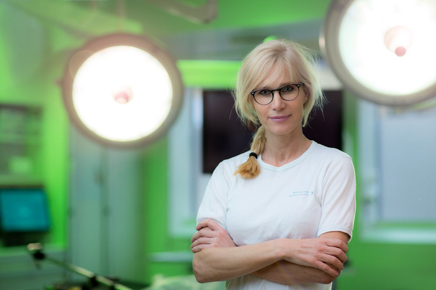 Medical professionals in a modern operating room with green lighting examining surgical equipment.