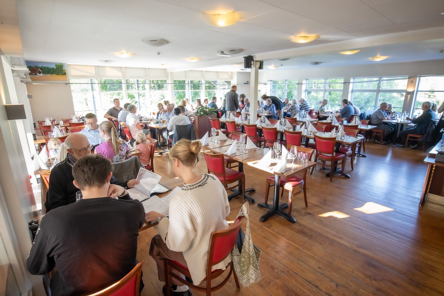 Spacious dining room with wooden floors and modern decor in warm natural lighting.
