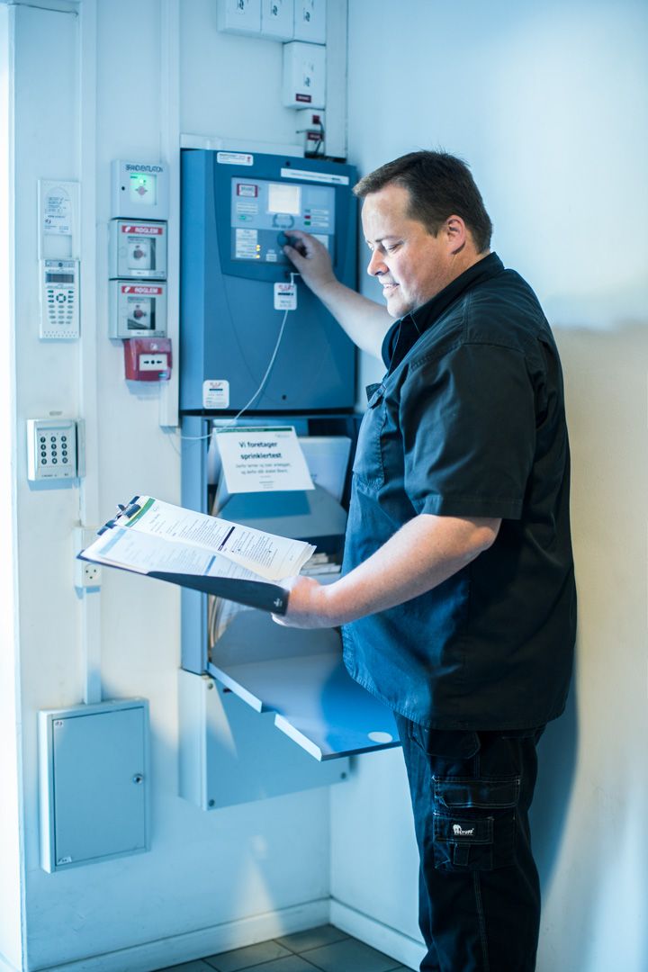Technician checking control panels and taking notes on clipboard.