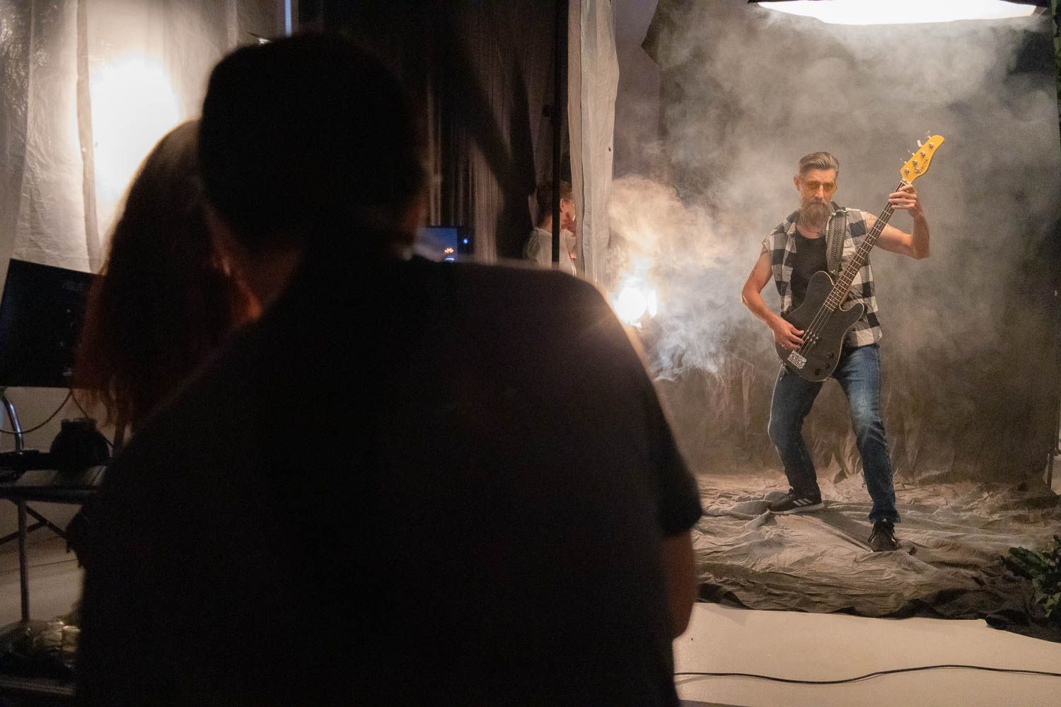 Behind the scenes view of a smoky photo shoot with dramatic lighting and equipment setup.
