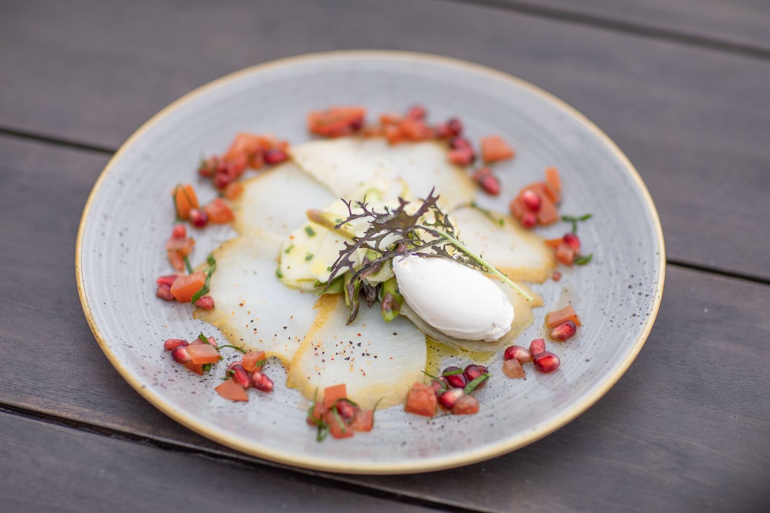 Poached eggs topped with fresh herbs and surrounded by crispy bacon bits on an artisanal plate.