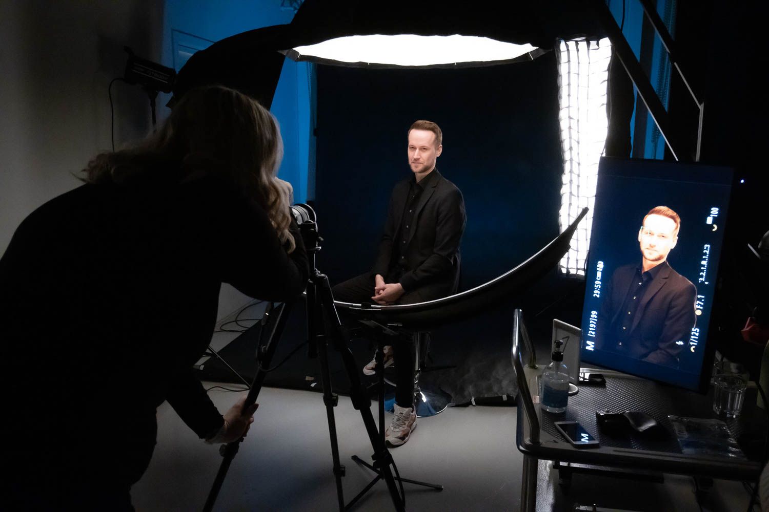 Dark studio environment with blue accent lighting and silhouetted photography equipment.